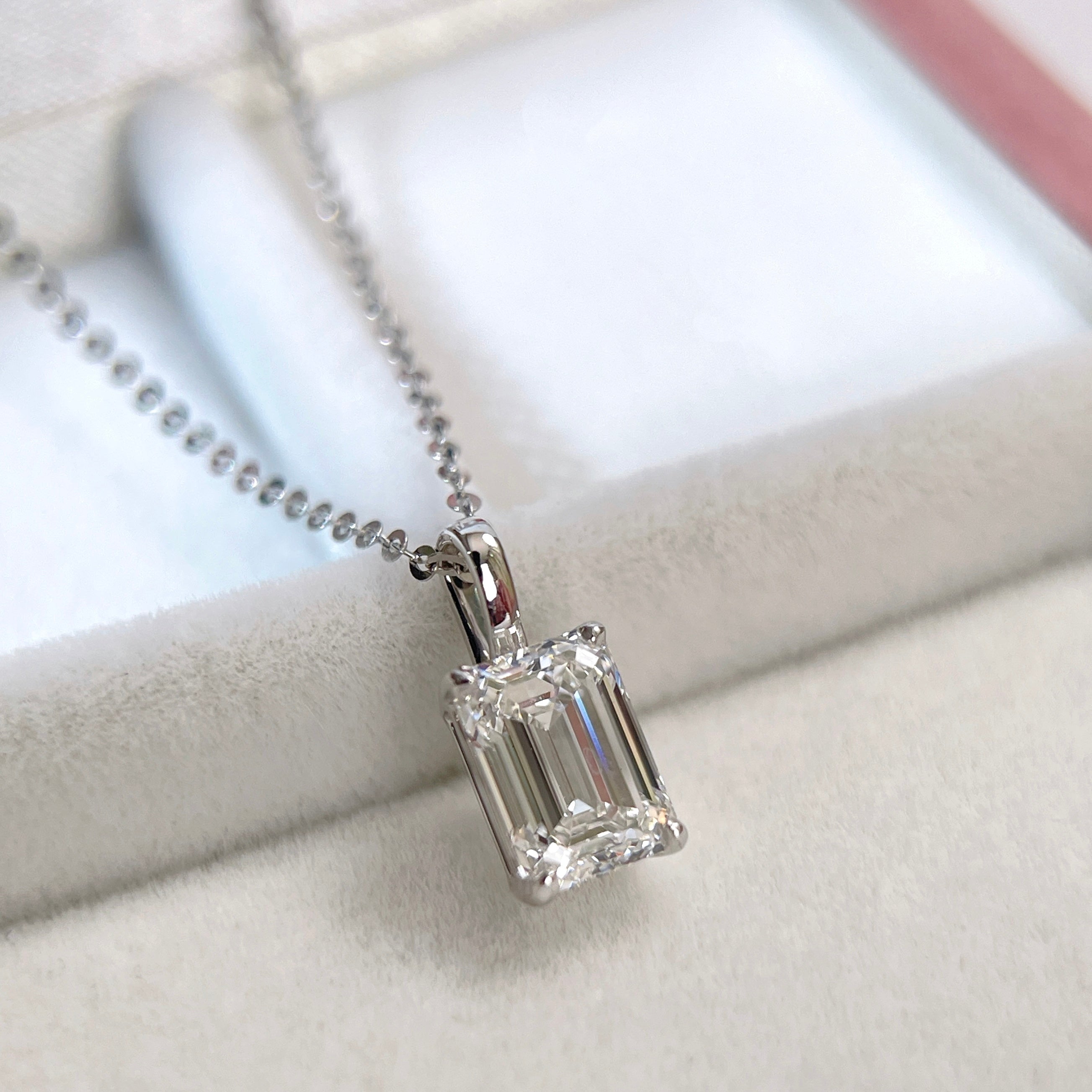 Angled display of a 1.5 ct emerald-cut lab grown diamond 14K white gold pendant styled on a chain