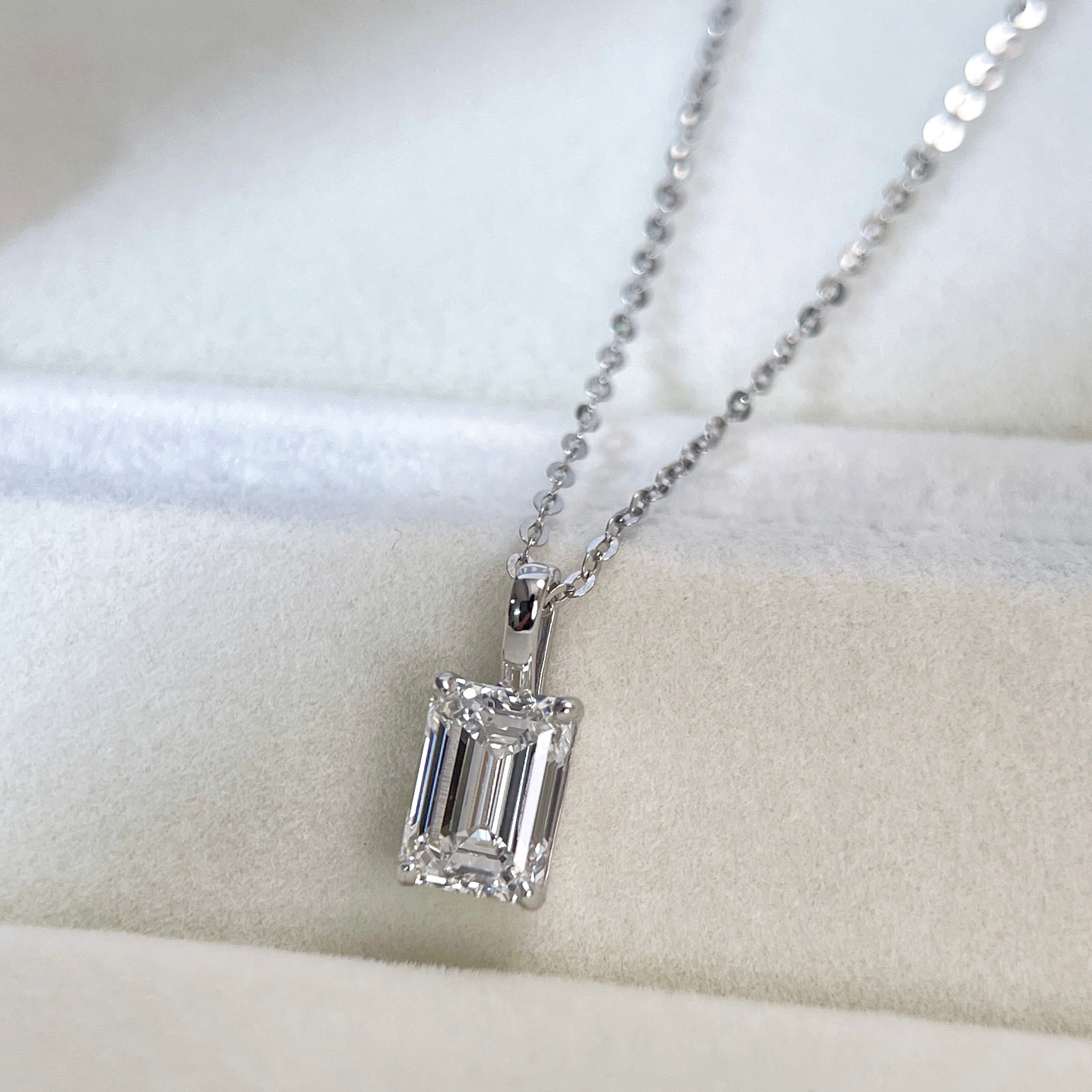 Close display of the four-prong setting and bail on an emerald-cut lab grown diamond pendant