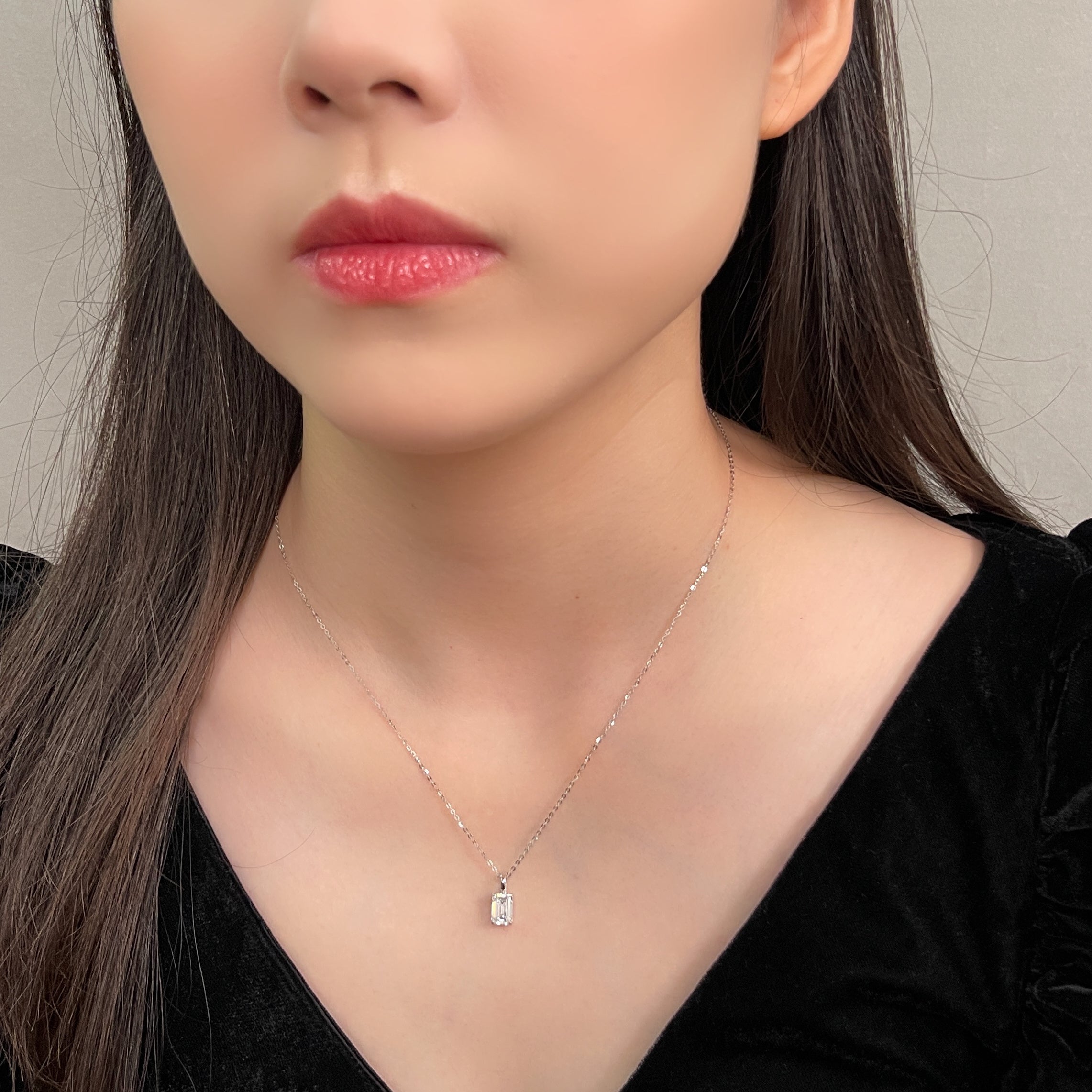 Model wearing a 1.5 ct emerald-cut lab grown diamond 14K white gold pendant styled on a chain
