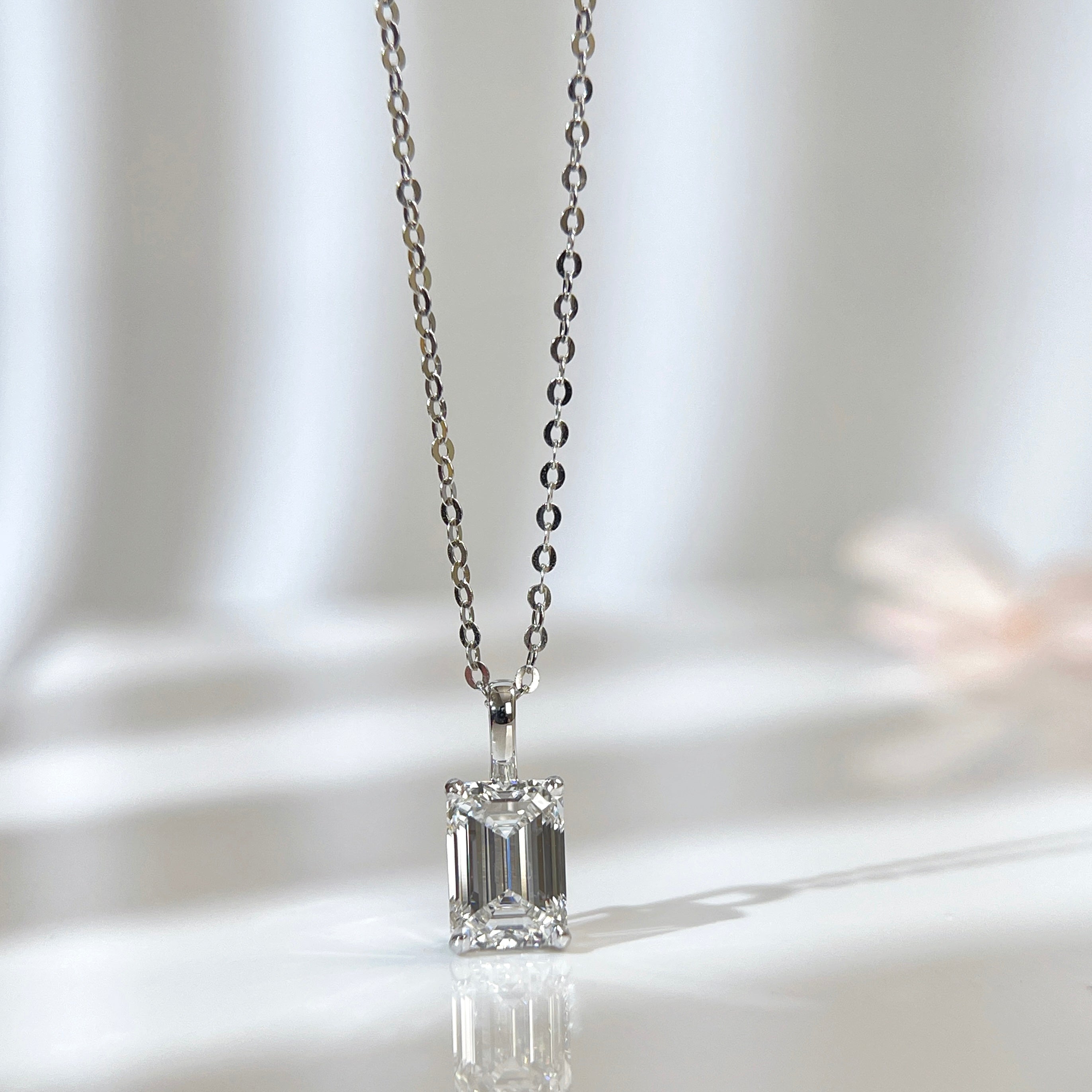 Angled reflective display of an emerald-cut lab grown diamond 14K white gold pendant on a chain