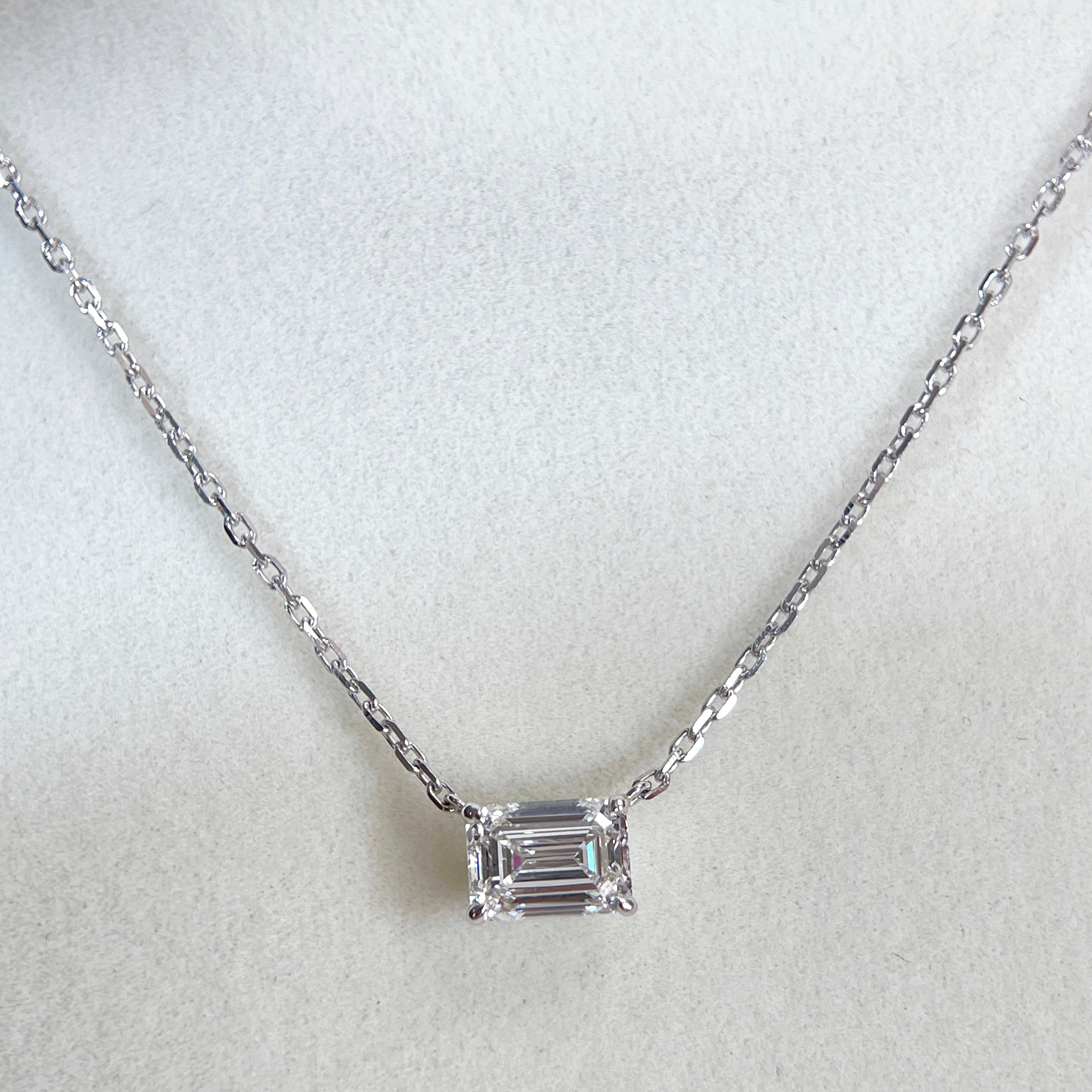 Centered display of a 1.5 ct emerald-cut lab grown diamond four-prong necklace in 18K white gold