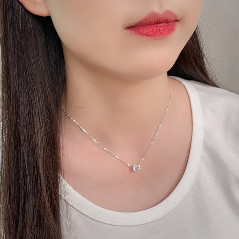 Model wearing a 1.5 ct emerald-cut lab grown diamond solitaire necklace in 18K white gold