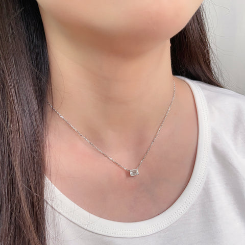 Close-up of an emerald-cut lab grown diamond 18K white gold necklace worn on the neck