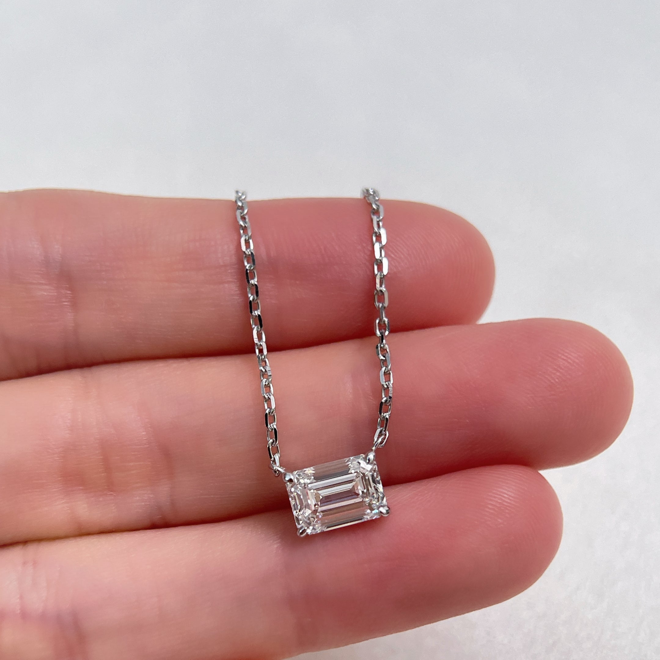Hand-held view showing the scale of a 1.5 ct emerald-cut lab grown diamond 18K white gold necklace