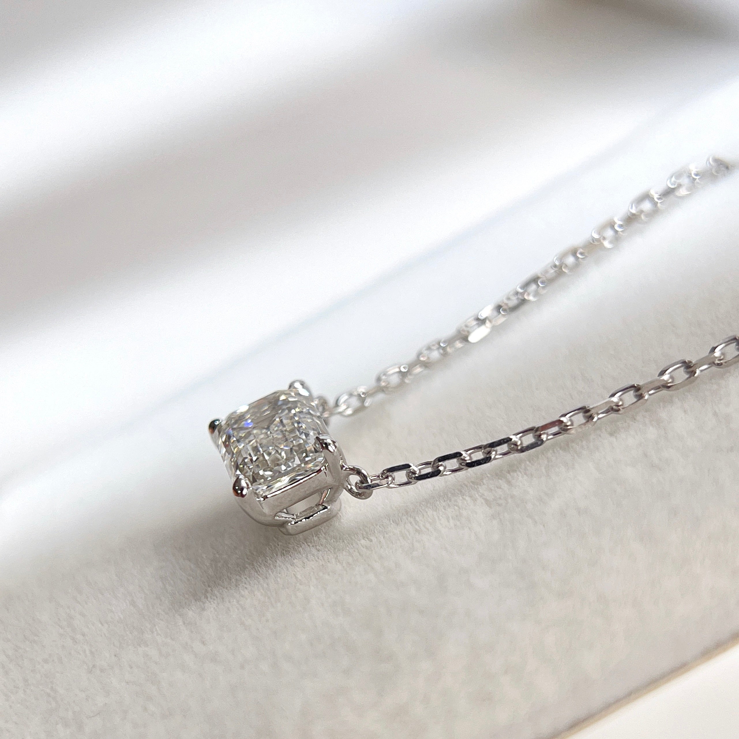 Side view showing the four-prong basket of an emerald-cut lab grown diamond 18K white gold necklace