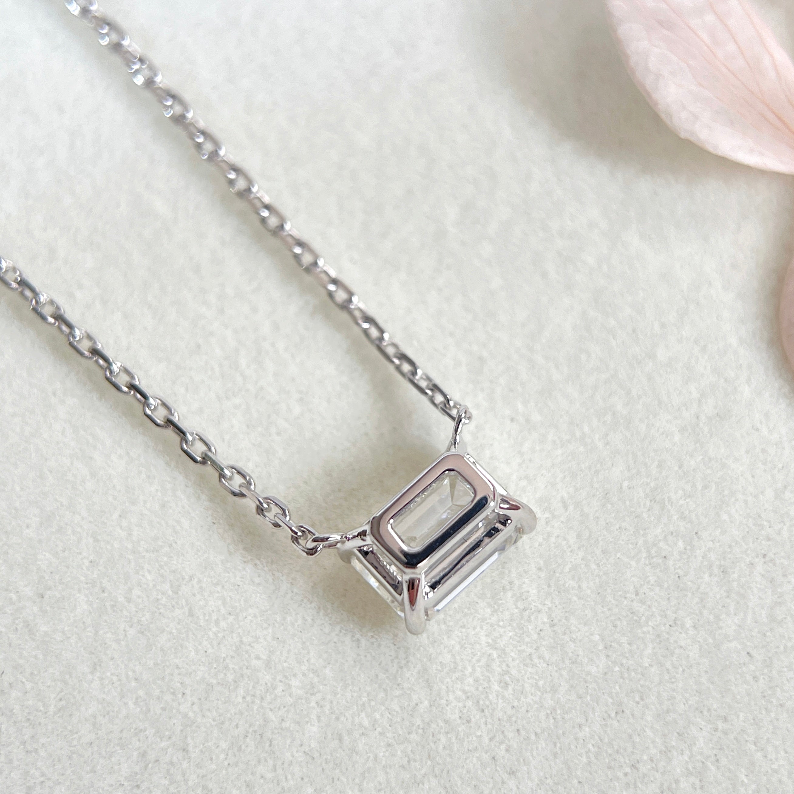 Back view showing the open basket setting of an emerald-cut lab grown diamond 18K white gold necklace