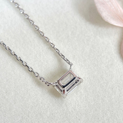Back view showing the open basket setting of an emerald-cut lab grown diamond 18K white gold necklace