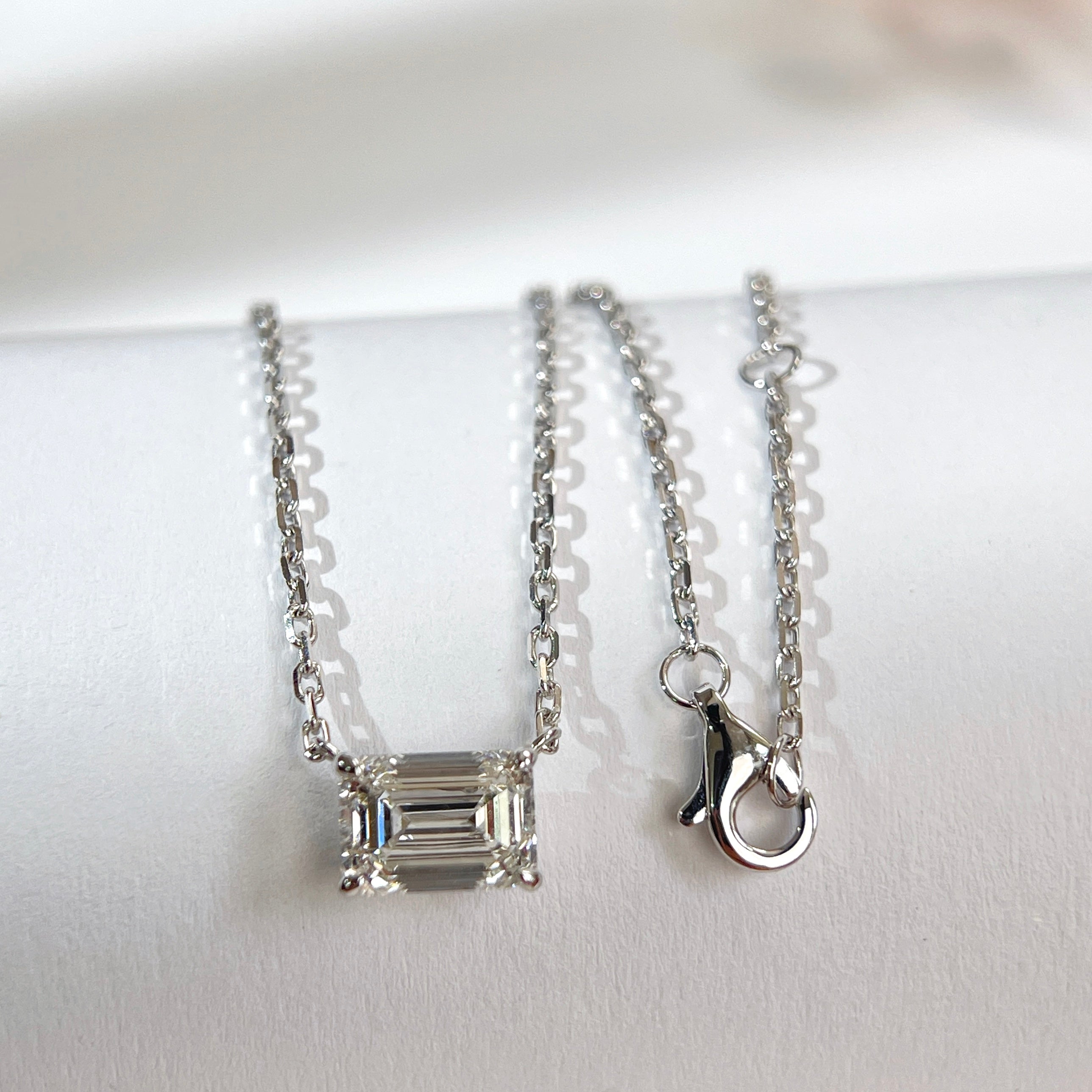 Emerald-cut lab grown diamond necklace with its 18K white gold chain and clasp displayed together