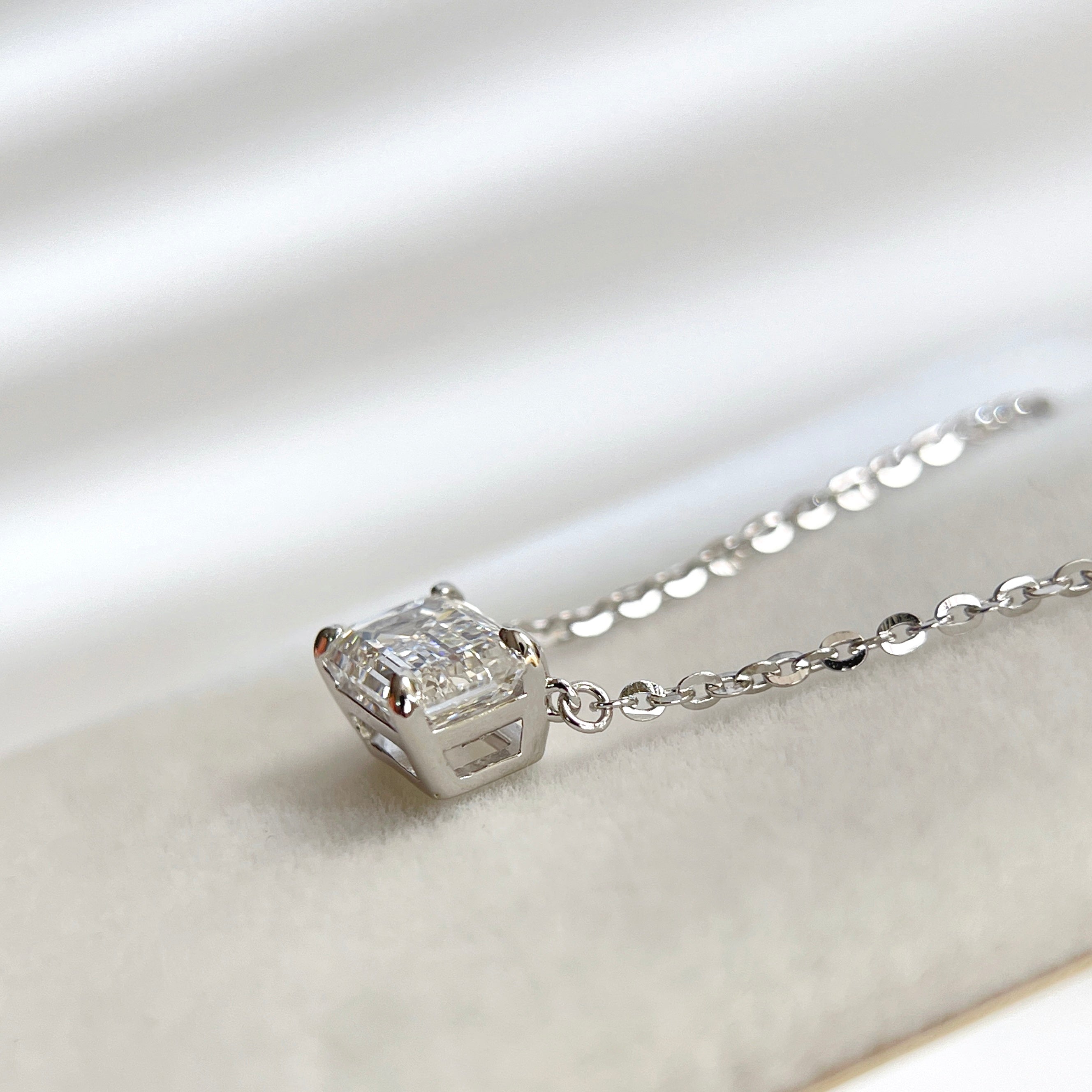Side view showing the four-prong basket of an emerald-cut lab grown diamond sterling silver necklace