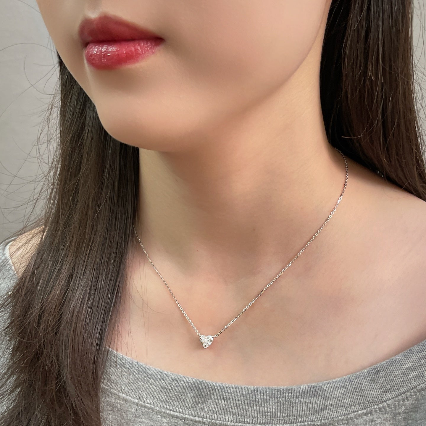 Side-profile view of a model wearing a 1.5 carat heart-shaped lab grown diamond necklace in S925 sterling silver.