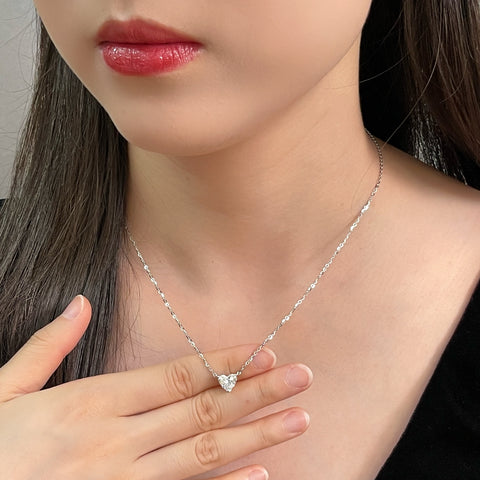 Model holding a 1.5 carat heart-shaped lab grown diamond necklace in S925 sterling silver.