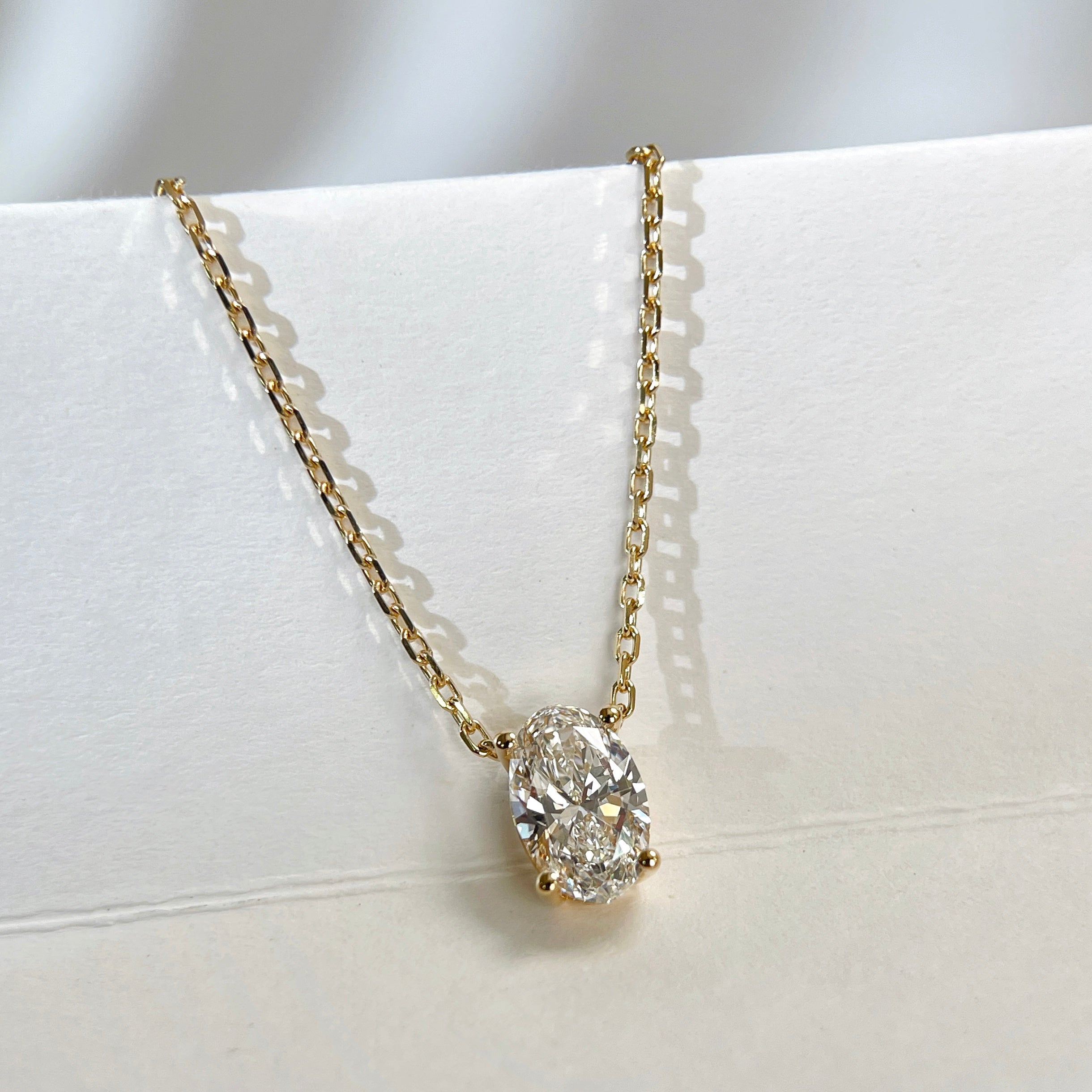 Angled display of a four-prong oval lab-grown diamond necklace