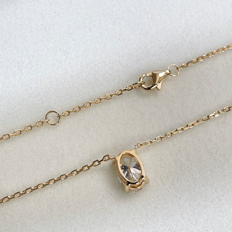 Back of the oval diamond setting and lobster clasp on an 18K yellow gold necklace