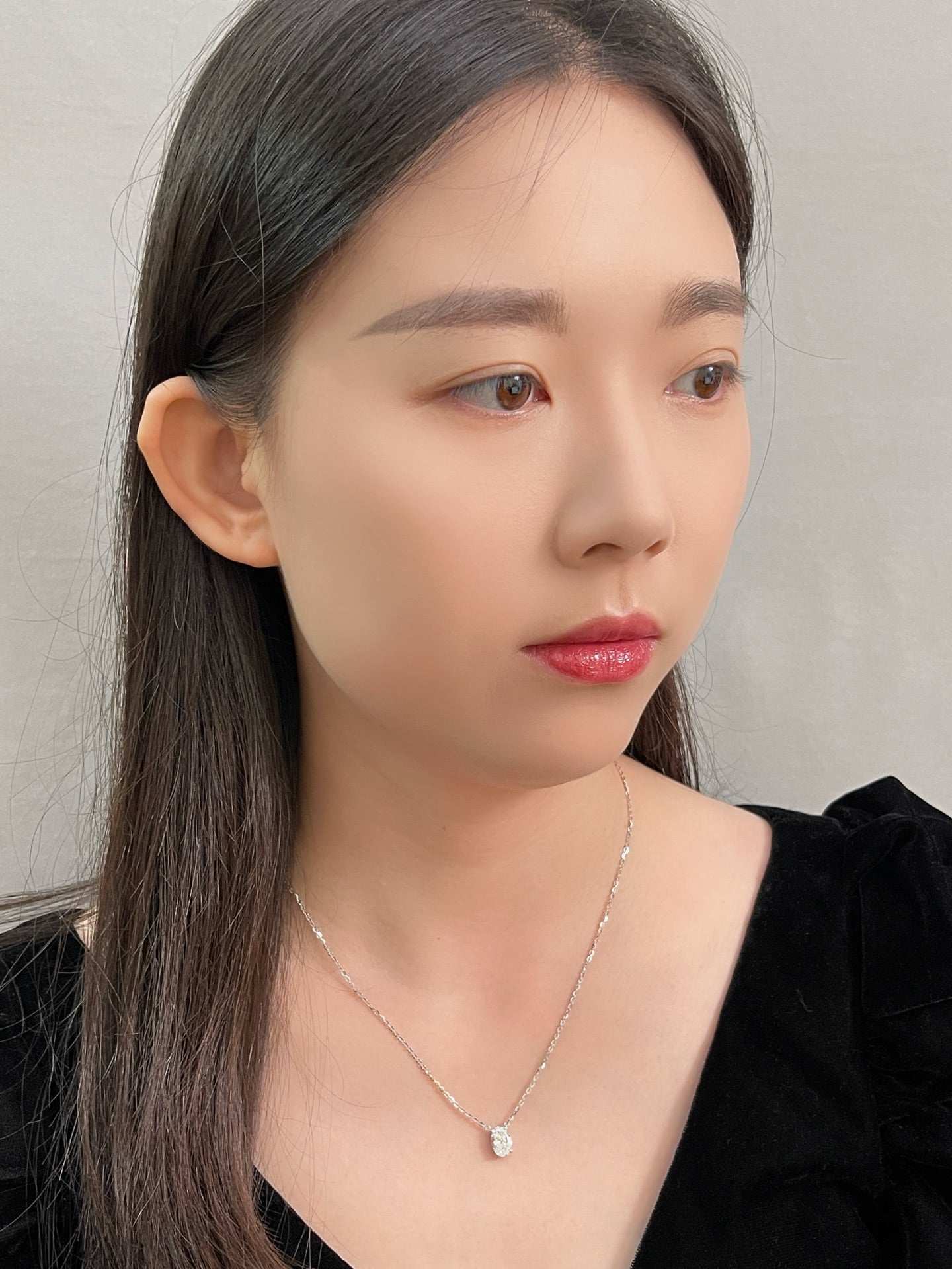 Portrait of a model wearing a 1.58 carat oval lab grown diamond necklace in 18K white gold.