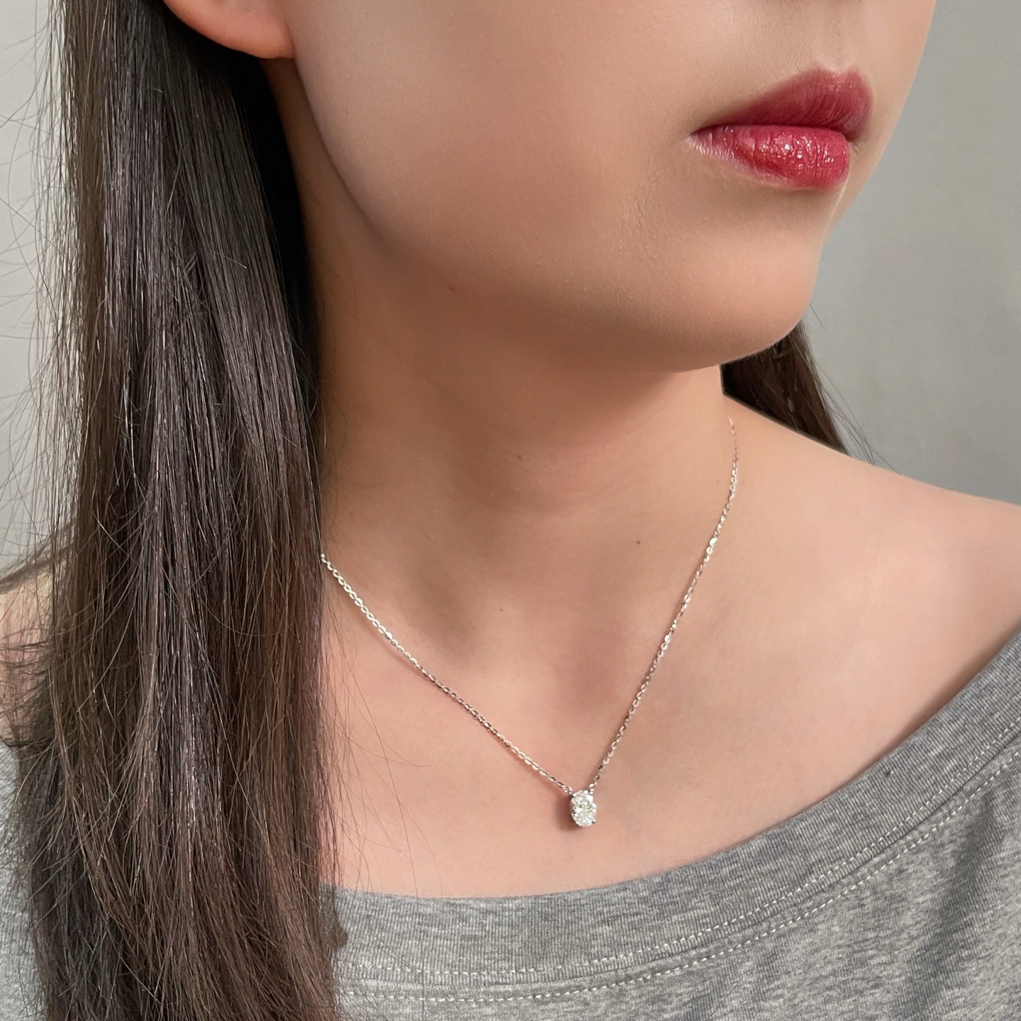 Side-profile view of a model wearing a 1.5 carat oval lab grown diamond necklace in S925 sterling silver.