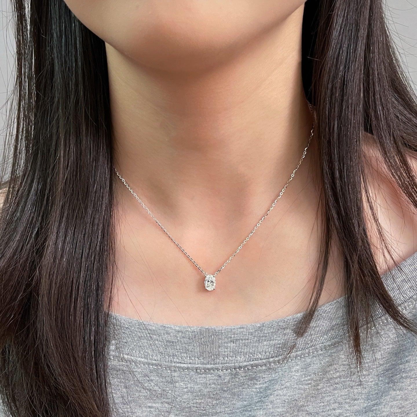 Full neckline view of a model wearing a 1.5 carat oval lab grown diamond necklace in S925 sterling silver.