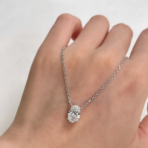 A 1.5 carat oval lab grown diamond necklace in S925 sterling silver displayed across a hand.