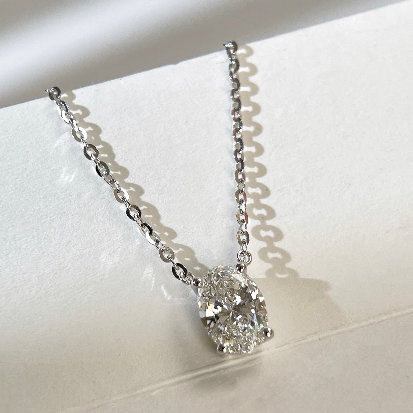 Angled view of a 1.5 carat oval lab grown diamond necklace in S925 sterling silver.