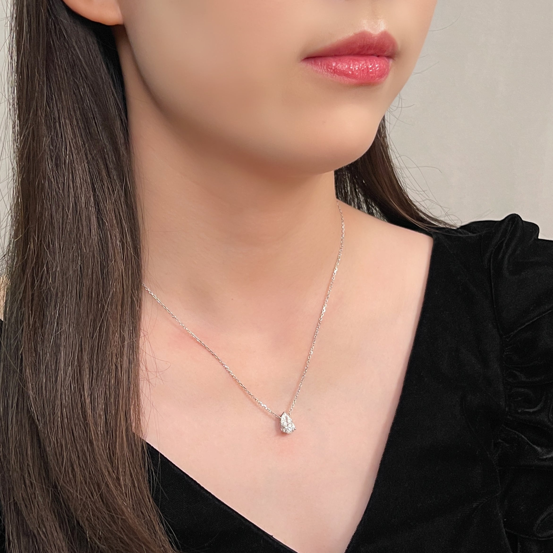 Side-profile view of a model wearing a 1.5 carat pear lab grown diamond necklace in 18K white gold.