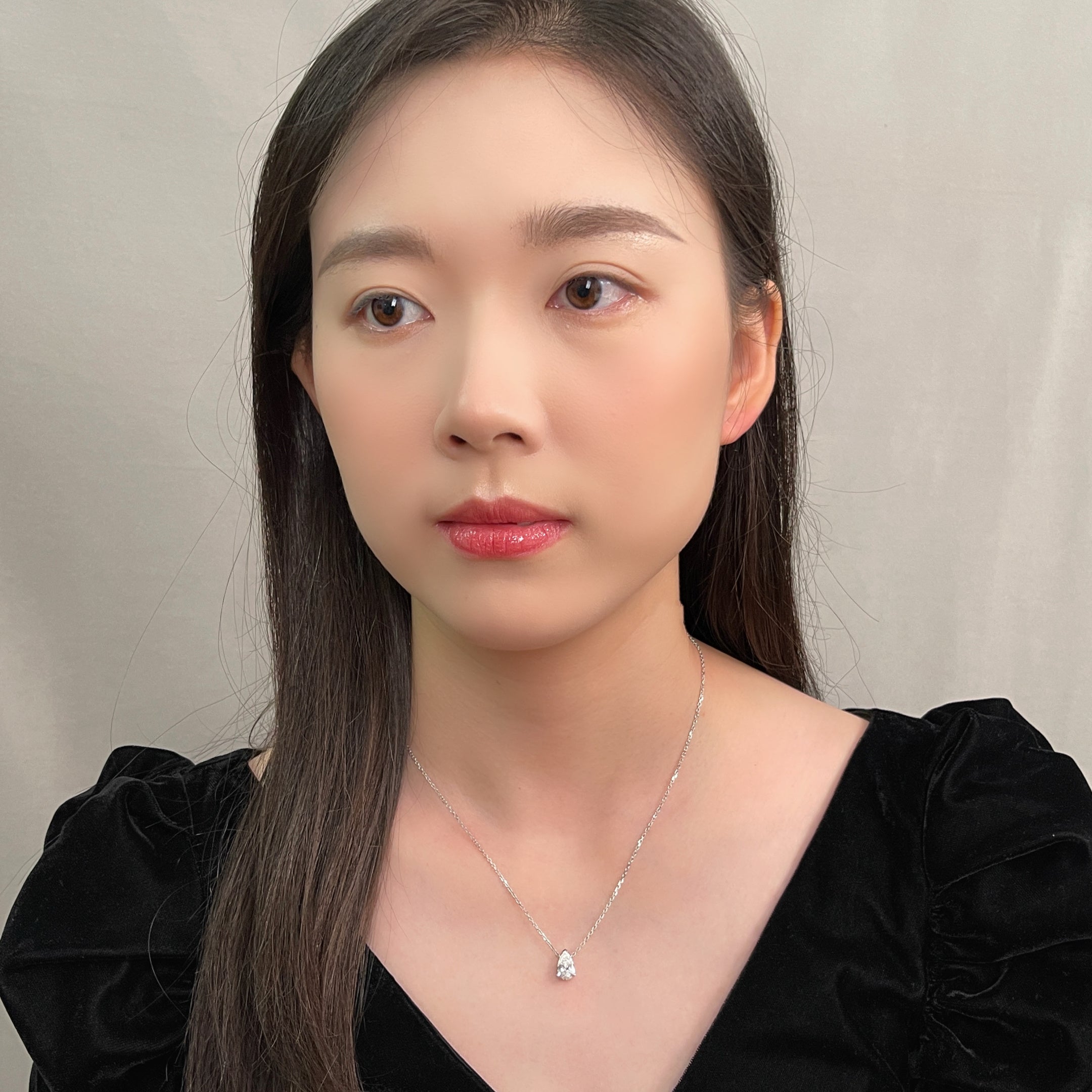 Portrait of a model wearing a 1.5 carat pear lab grown diamond necklace in 18K white gold.