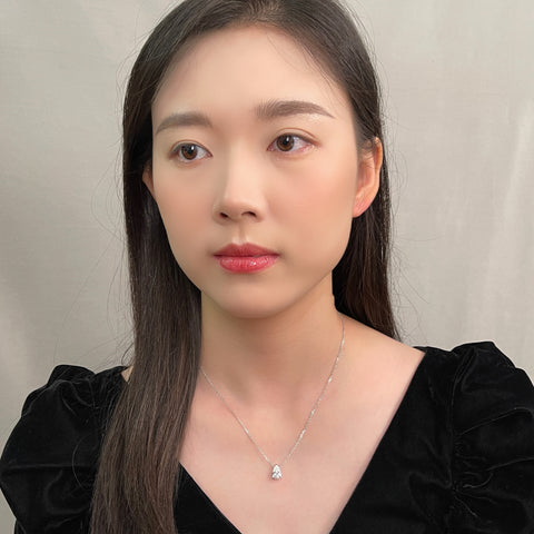 Portrait of a model wearing a 1.5 carat pear lab grown diamond necklace in 18K white gold.