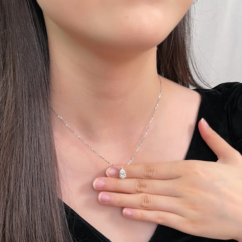 Model holding a 1.5 carat pear lab grown diamond necklace in 18K white gold.