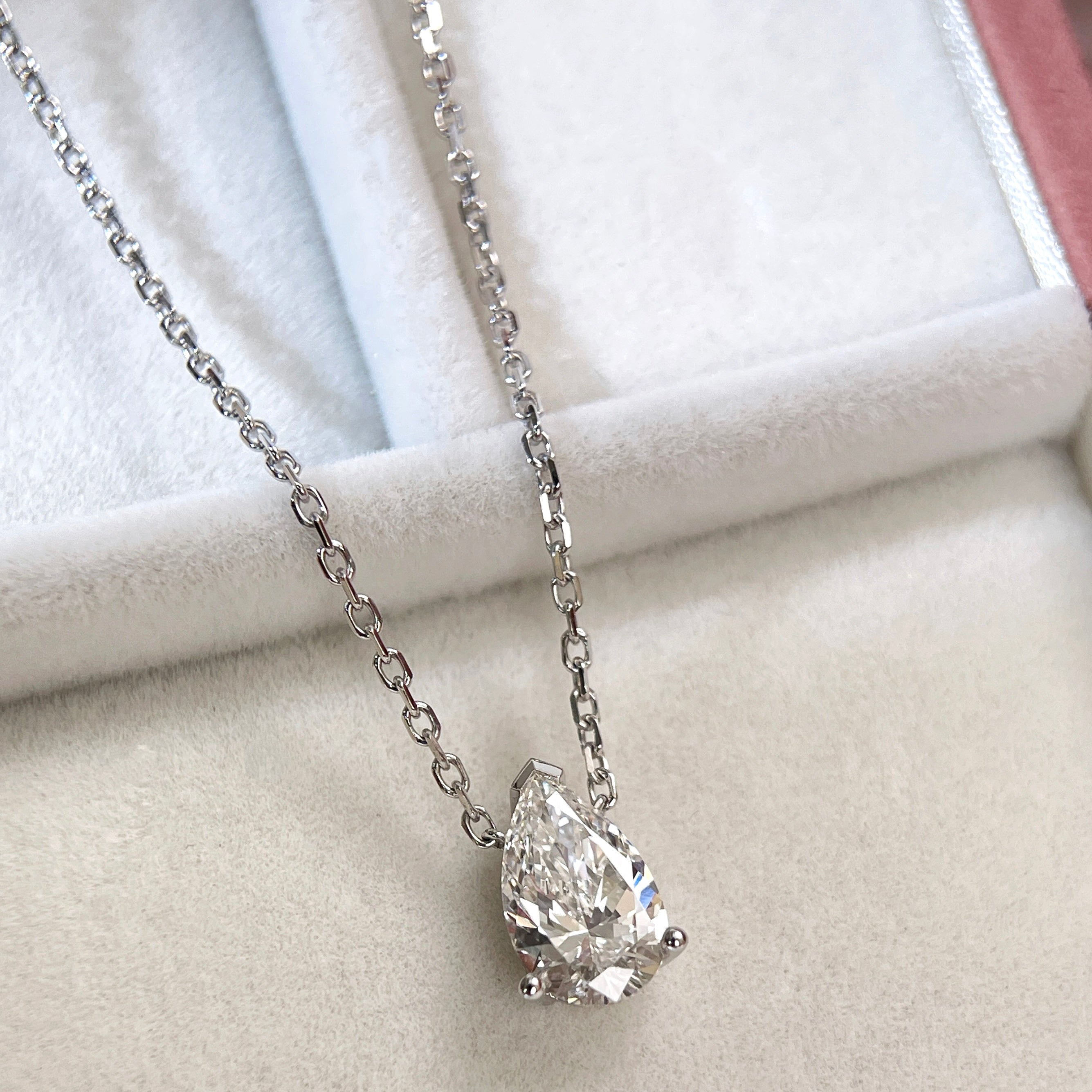Close-up showing the three-prong setting of a 1.5 carat pear lab grown diamond necklace in 18K white gold.