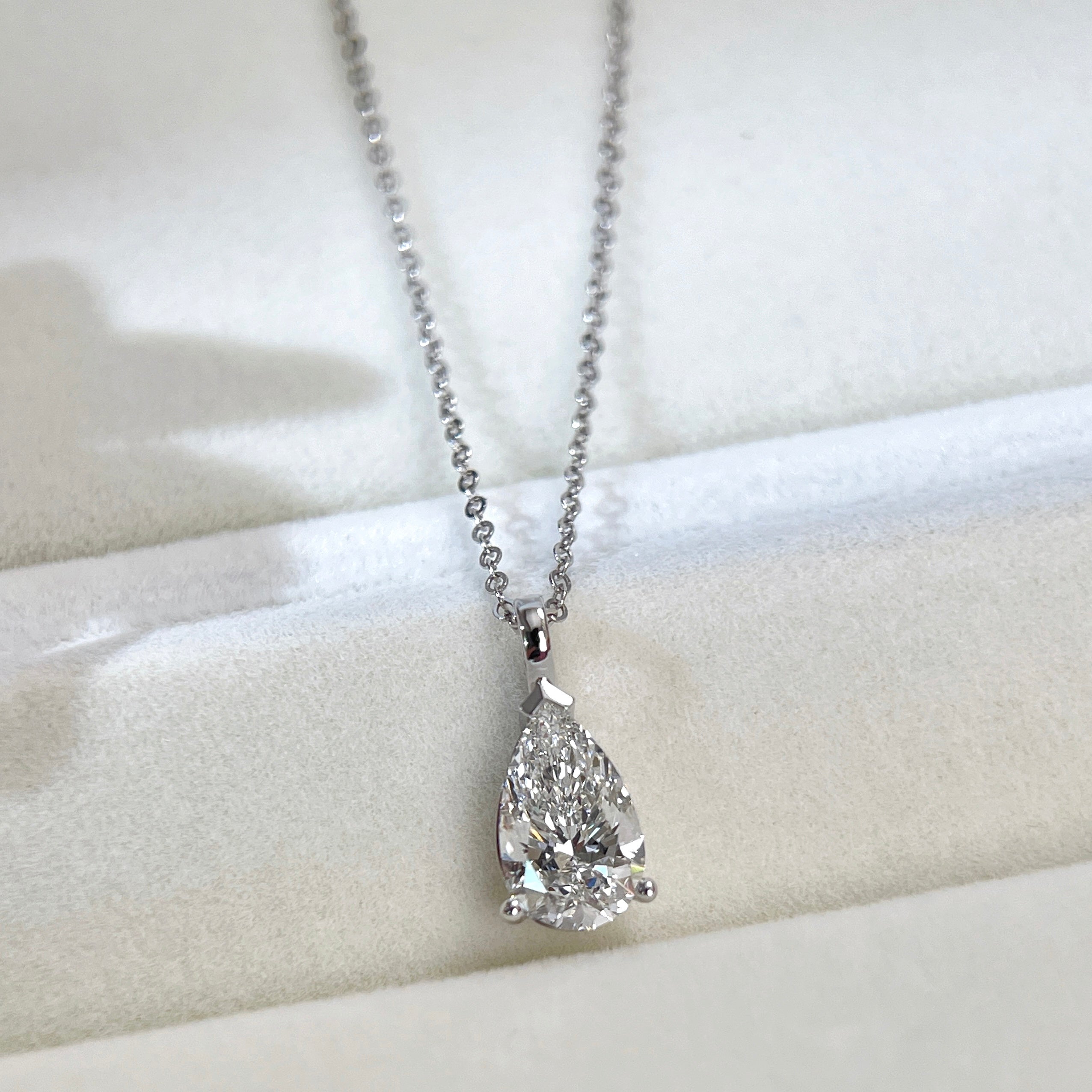 Jewelry display of a 1.5 carat pear lab grown diamond pendant in 14K white gold styled on a chain; chain not included.