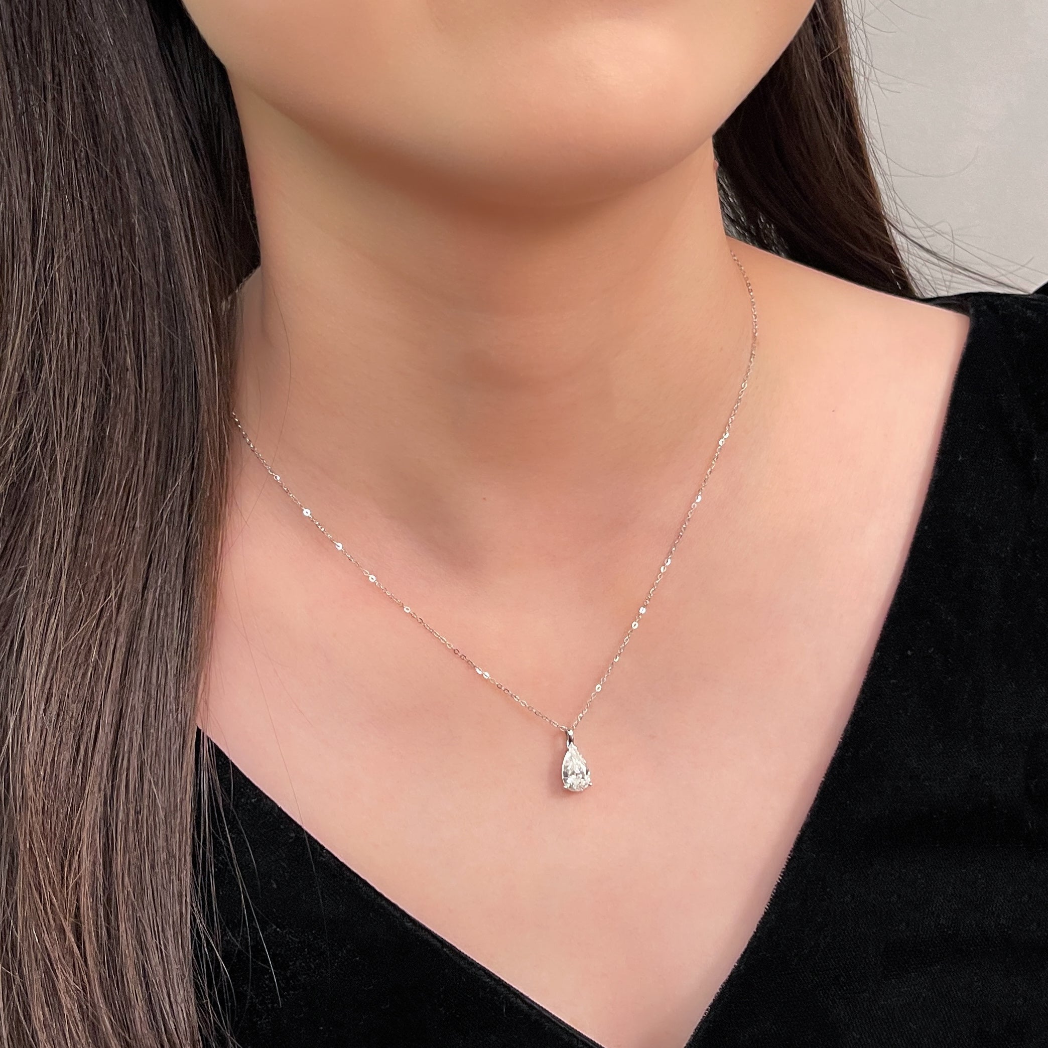Model wearing a 1.5 carat pear lab grown diamond pendant in 14K white gold styled on a chain; chain not included.