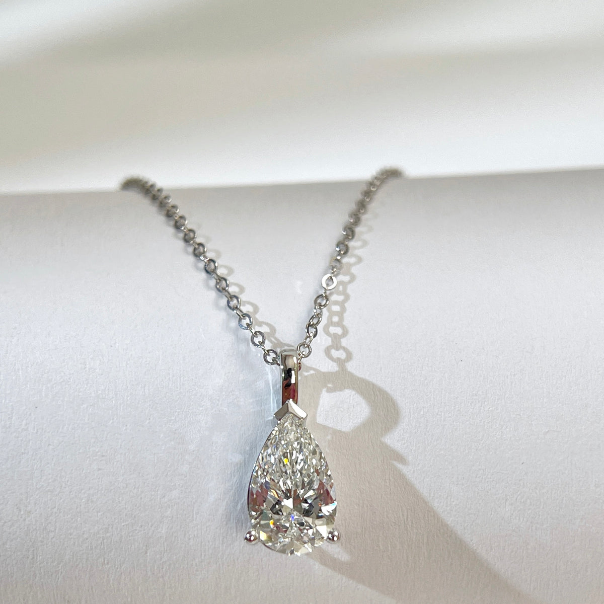 Diamond detail of a 1.5 carat pear lab grown diamond pendant in 14K white gold styled on a chain; chain not included.