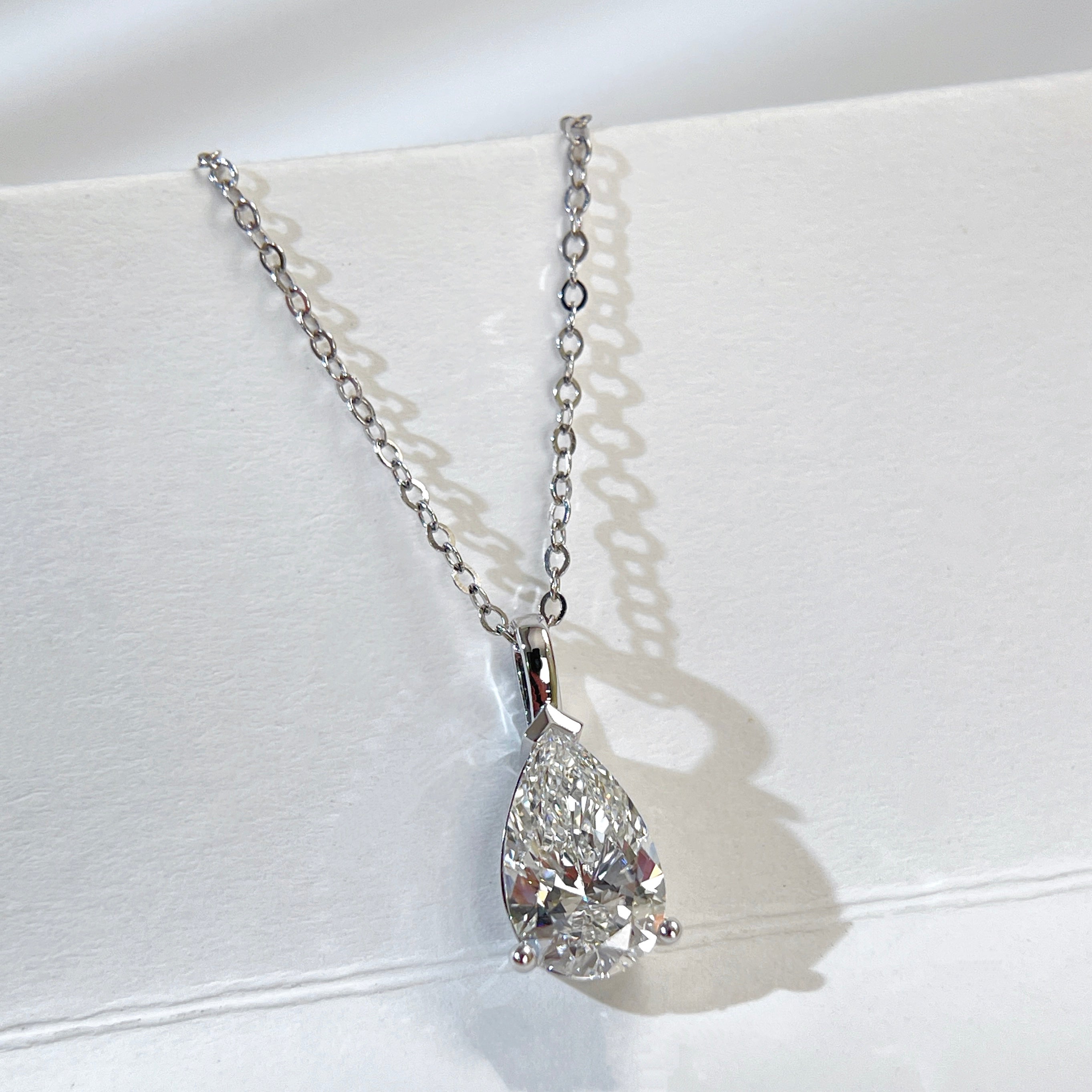 Jewelry display of a 1.5 carat pear lab grown diamond pendant in 14K white gold styled on a chain; chain not included.