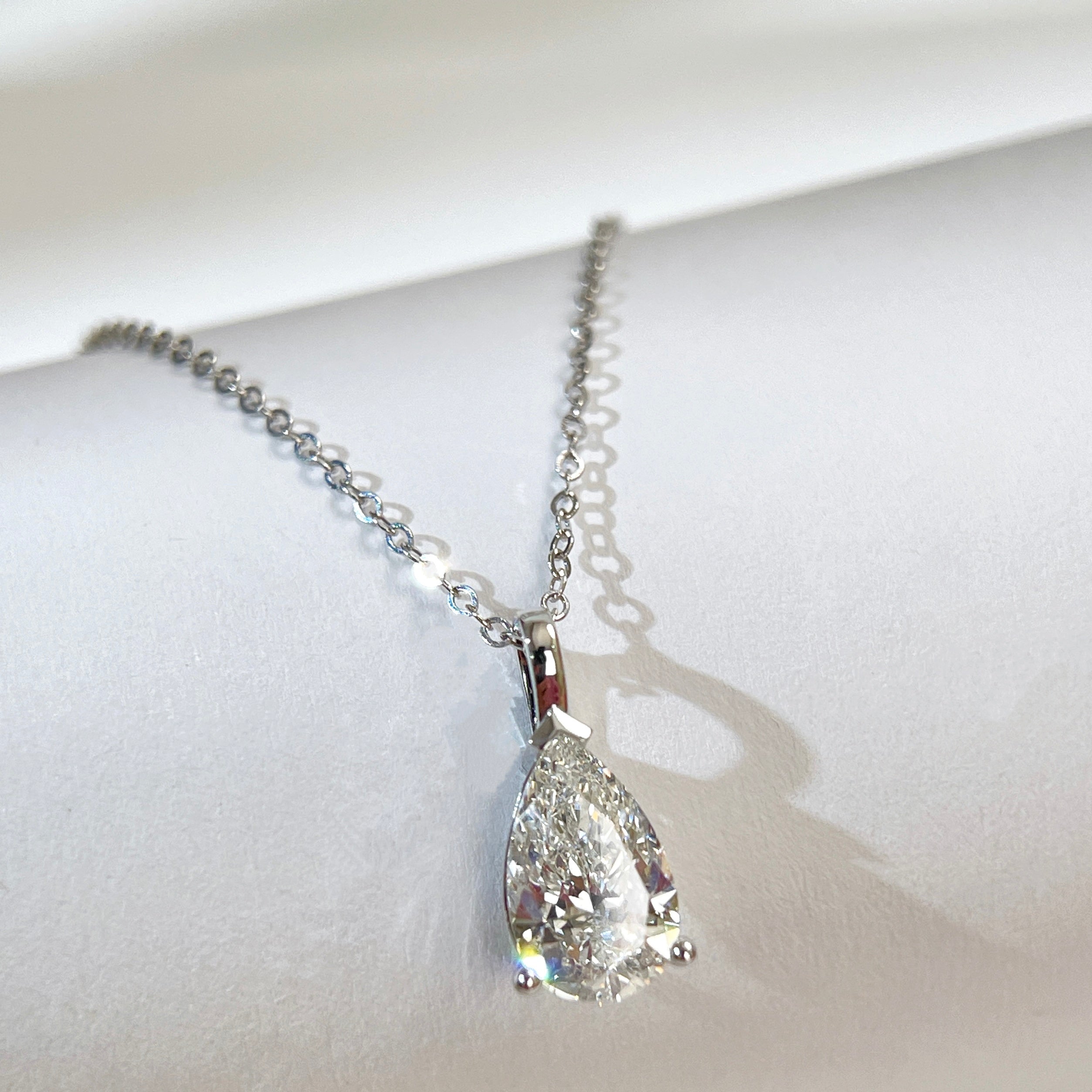 Jewelry display of a 1.5 carat pear lab grown diamond pendant in 14K white gold styled on a chain; chain not included.