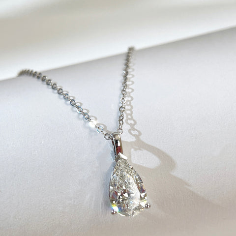 Jewelry display of a 1.5 carat pear lab grown diamond pendant in 14K white gold styled on a chain; chain not included.