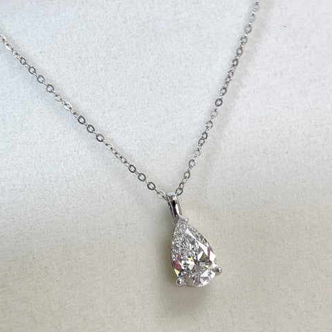 Angled view of a 1.5 carat pear lab grown diamond pendant in 14K white gold styled on a chain; chain not included.
