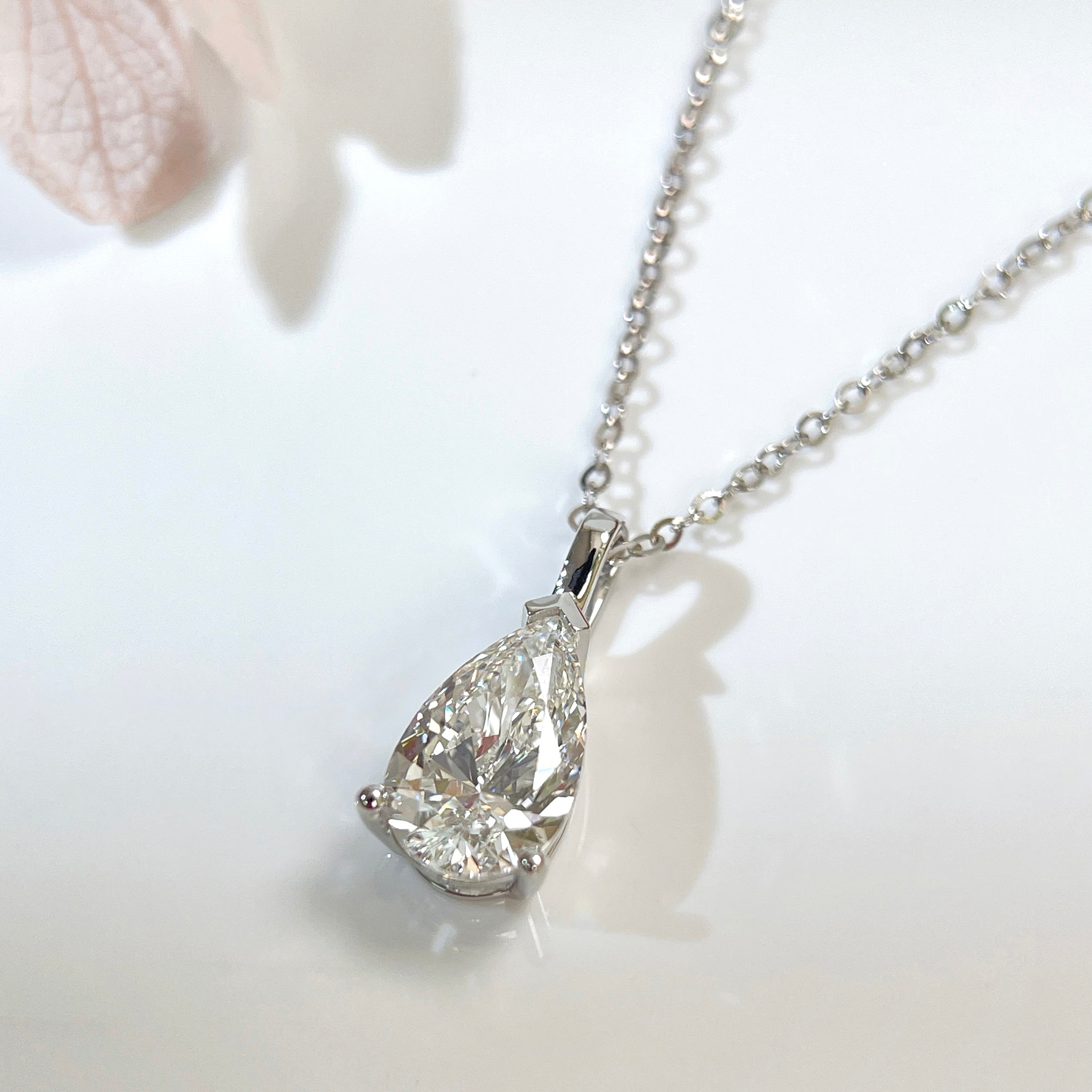 Close-up of a 1.5 carat pear lab grown diamond pendant in 14K white gold styled on a chain; chain not included.