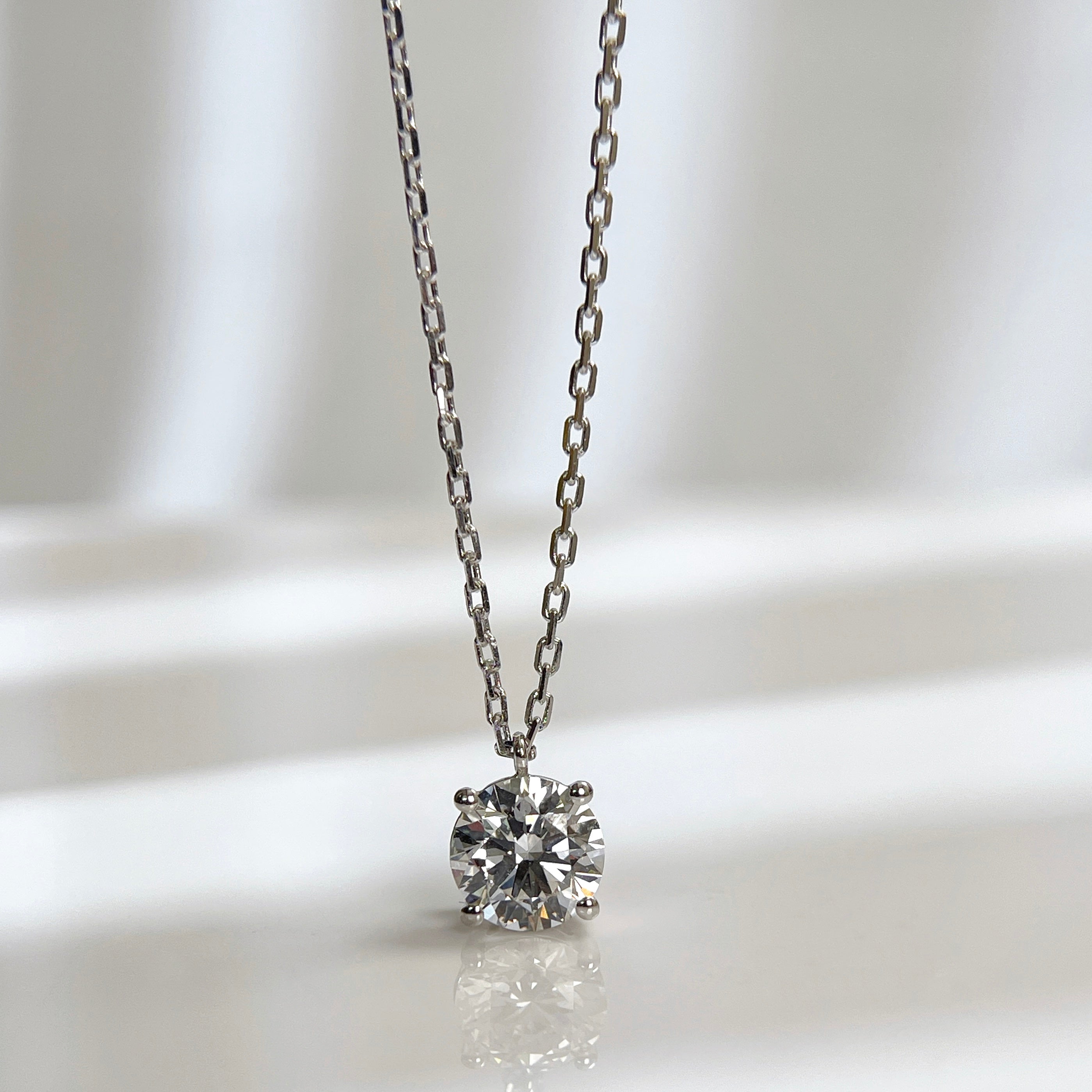 Front presentation of a 1.5 carat round lab grown diamond fixed pendant necklace in 18K white gold.