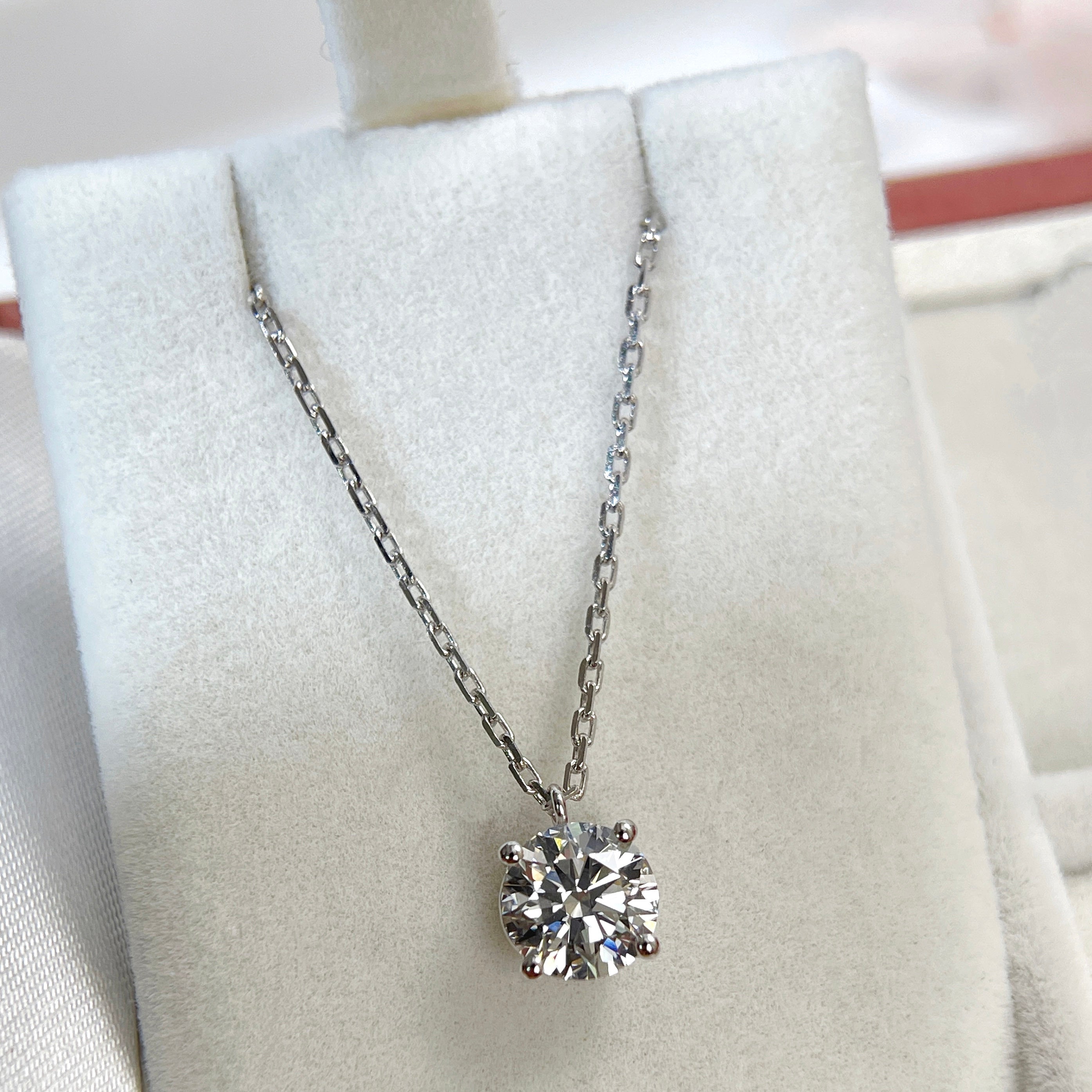 Jewelry display of a 1.5 carat round lab grown diamond fixed pendant necklace in 18K white gold.