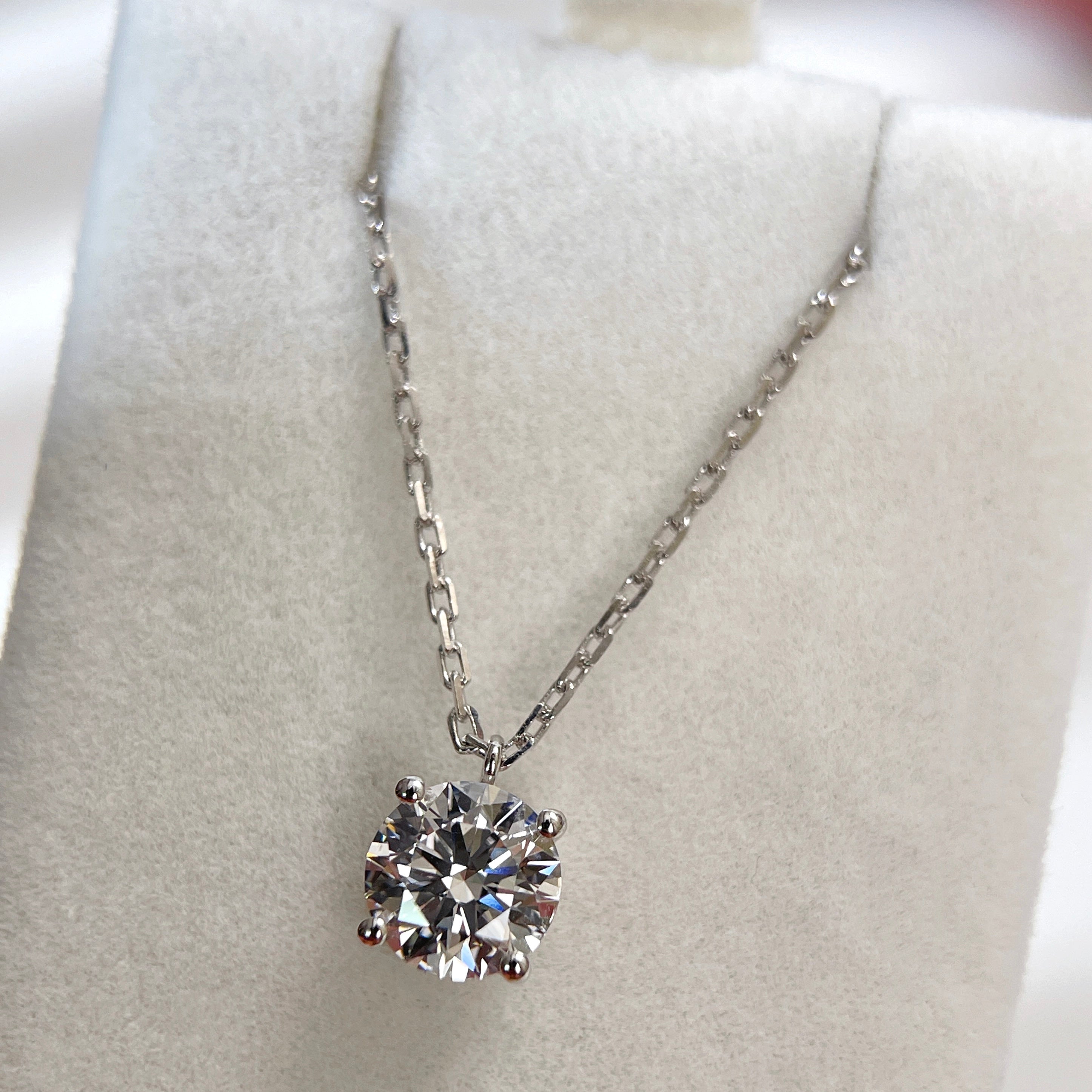 Jewelry display of a 1.5 carat round lab grown diamond fixed pendant necklace in 18K white gold.
