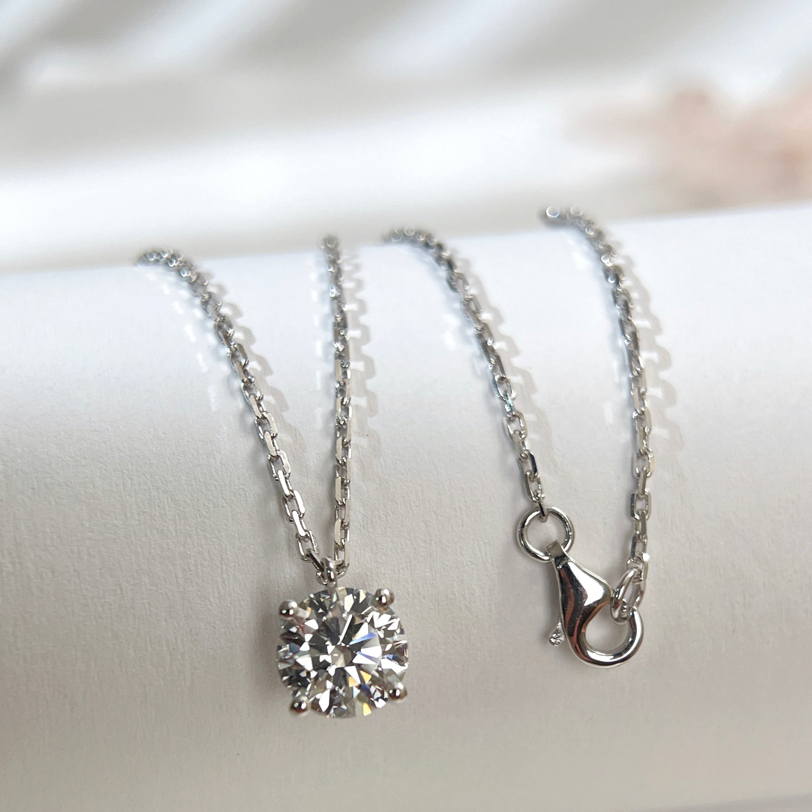 Substantial square-link chain and lobster clasp detail on an 18K white gold diamond necklace.