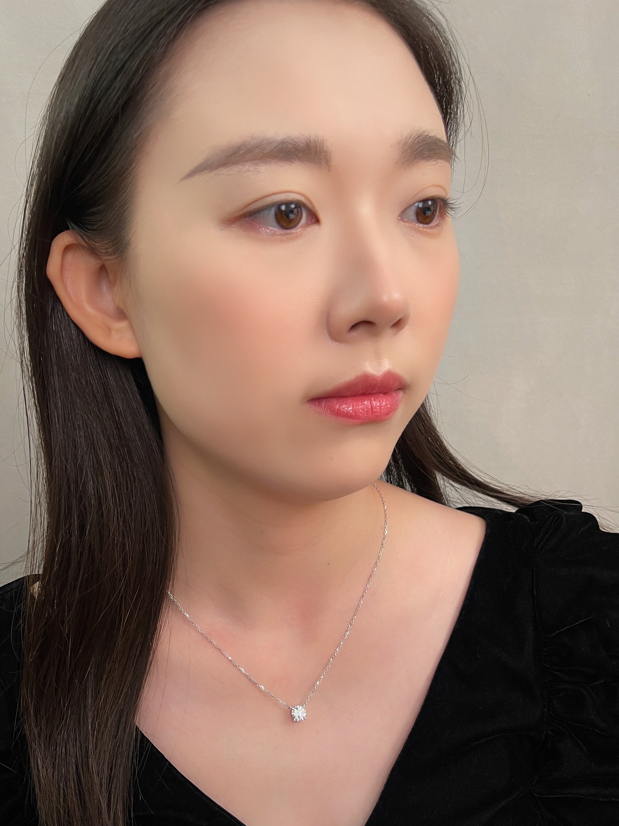 Side-profile view of a model wearing a 1.5 carat round lab grown diamond necklace in 18K white gold.