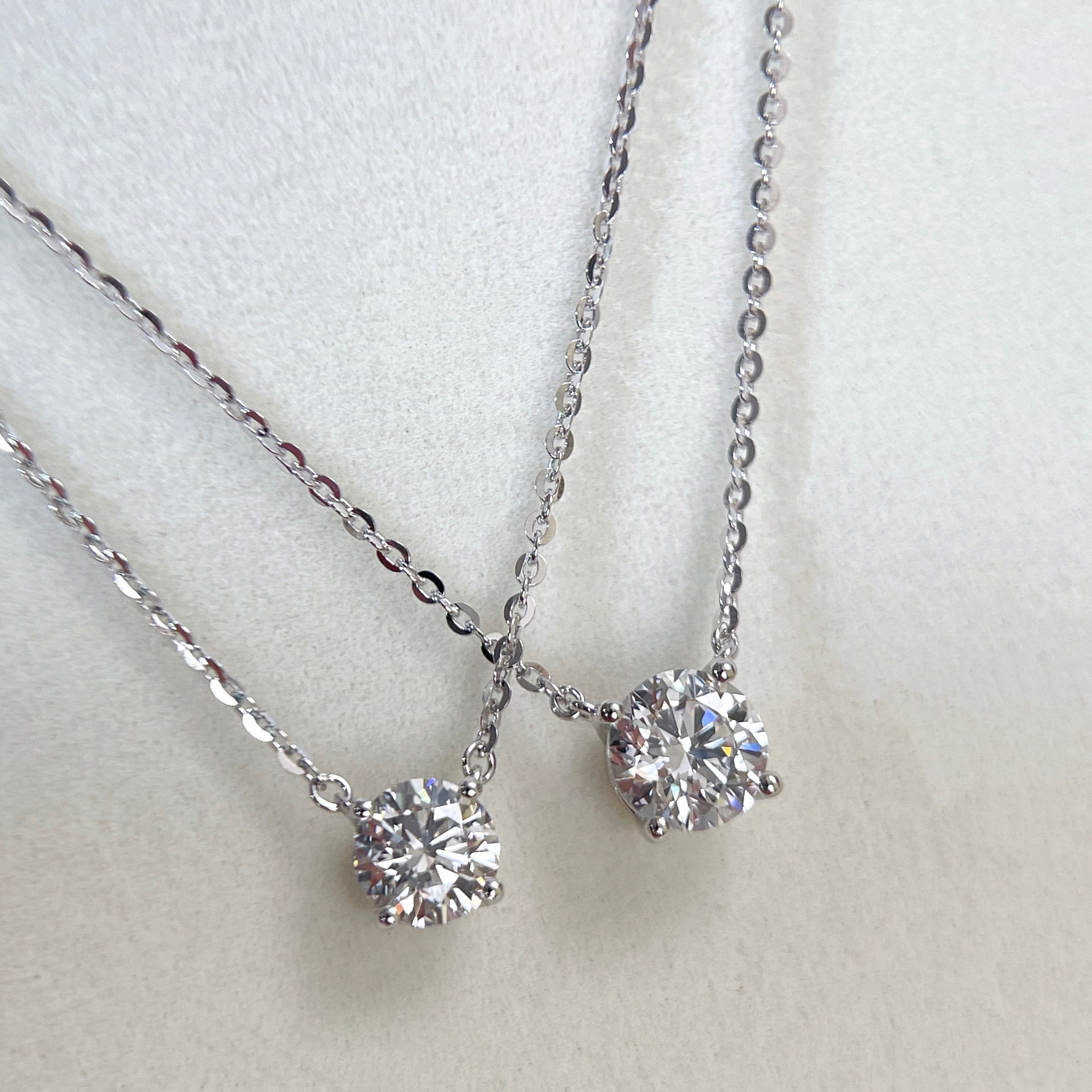 Angled view comparing 1 CT and 1.5 CT round lab grown diamond necklaces.