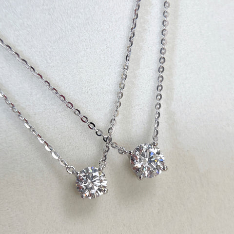 Angled view comparing 1 CT and 1.5 CT round lab grown diamond necklaces.