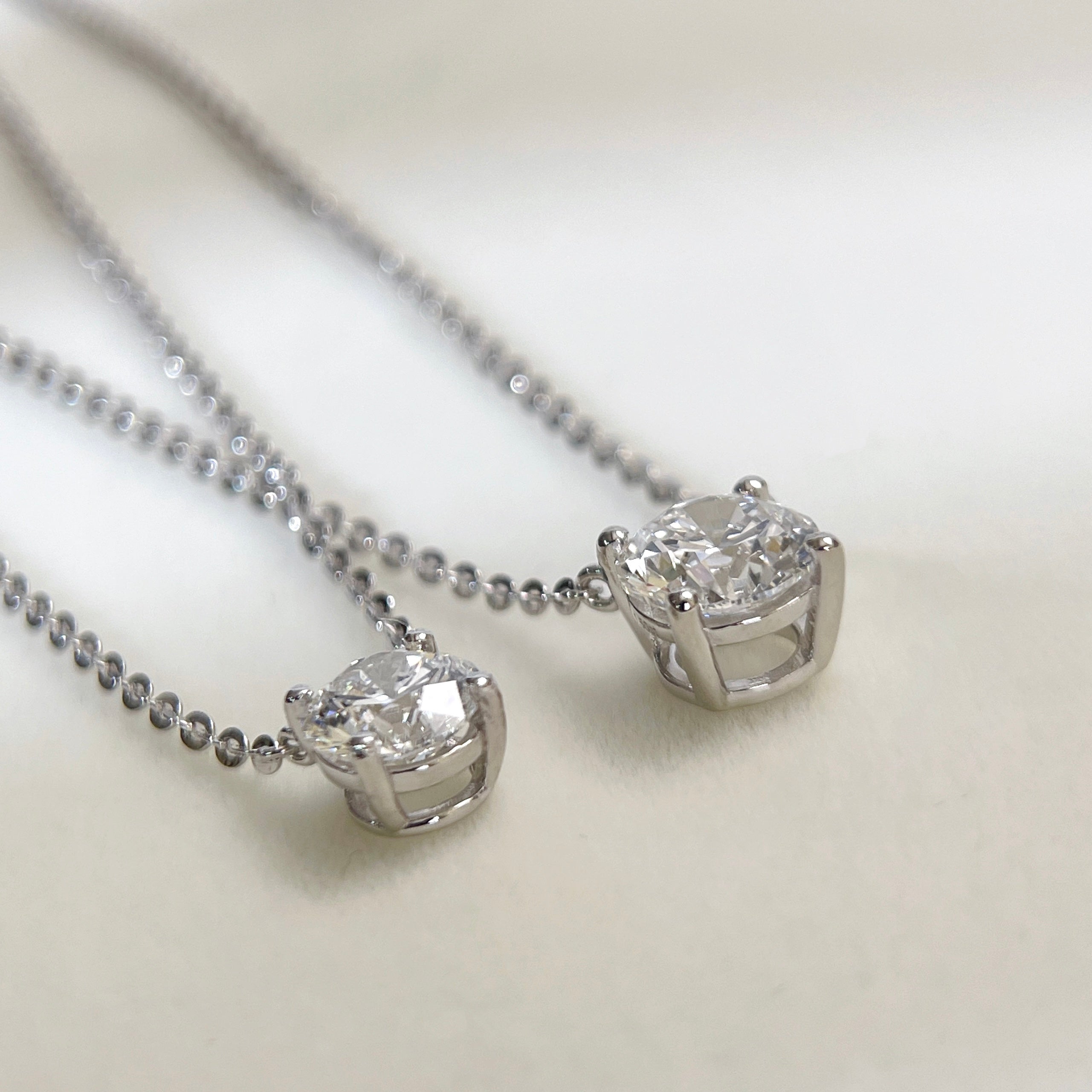 Back setting view comparing 1 CT and 1.5 CT round lab grown diamond necklaces.