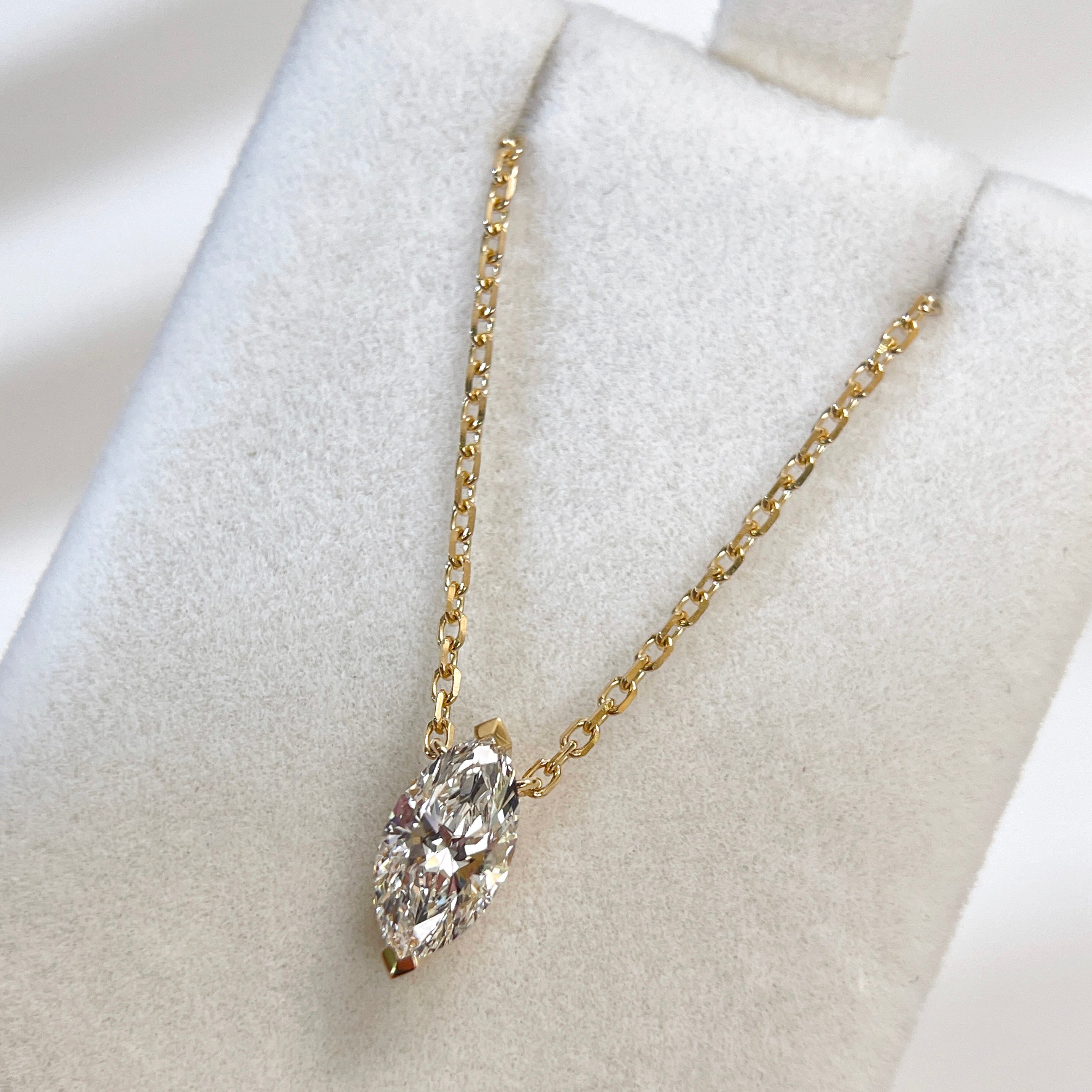 Jewelry display of a 1 carat marquise lab grown diamond necklace in 18K yellow gold.