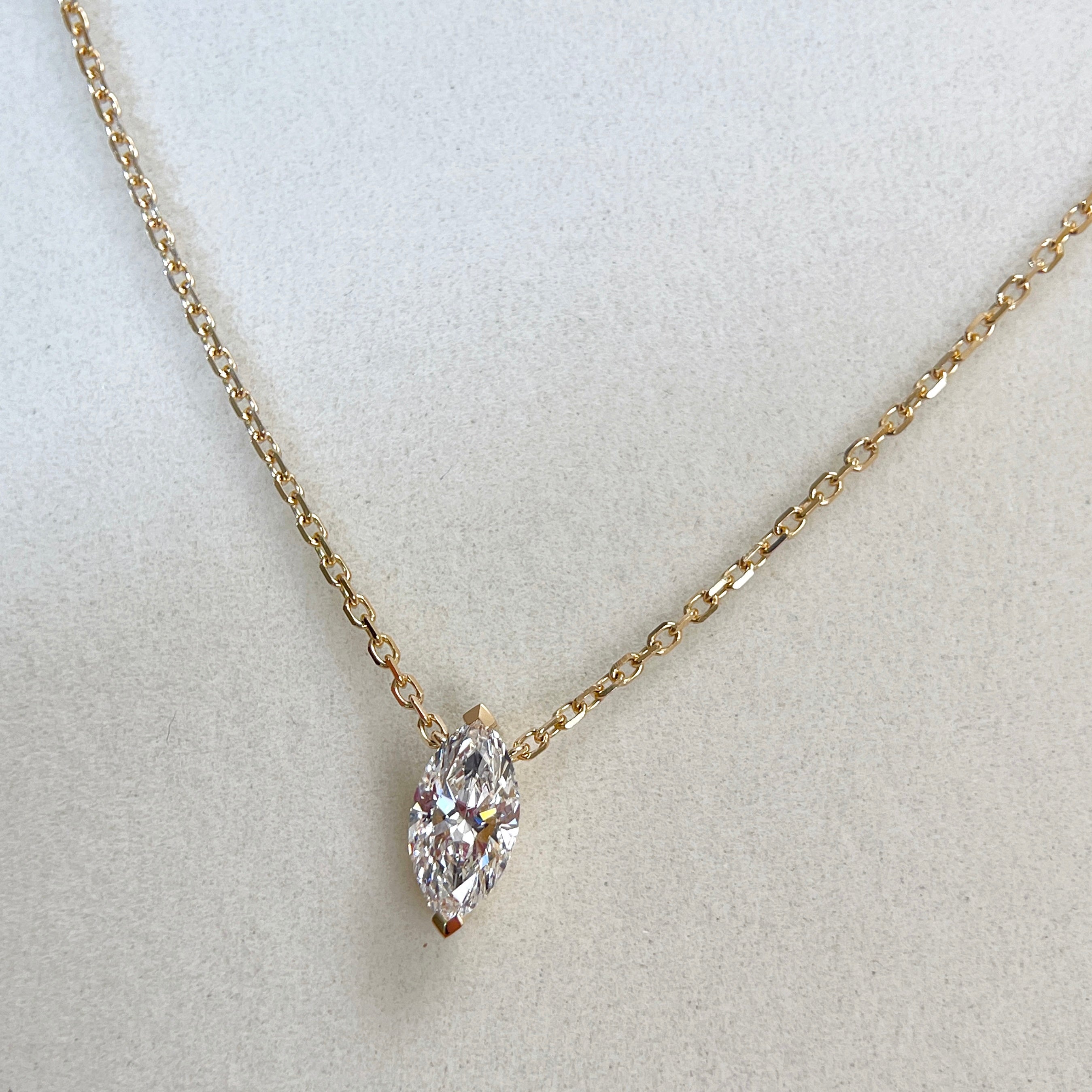 Jewelry display of a 1 carat marquise lab grown diamond necklace in 18K yellow gold.