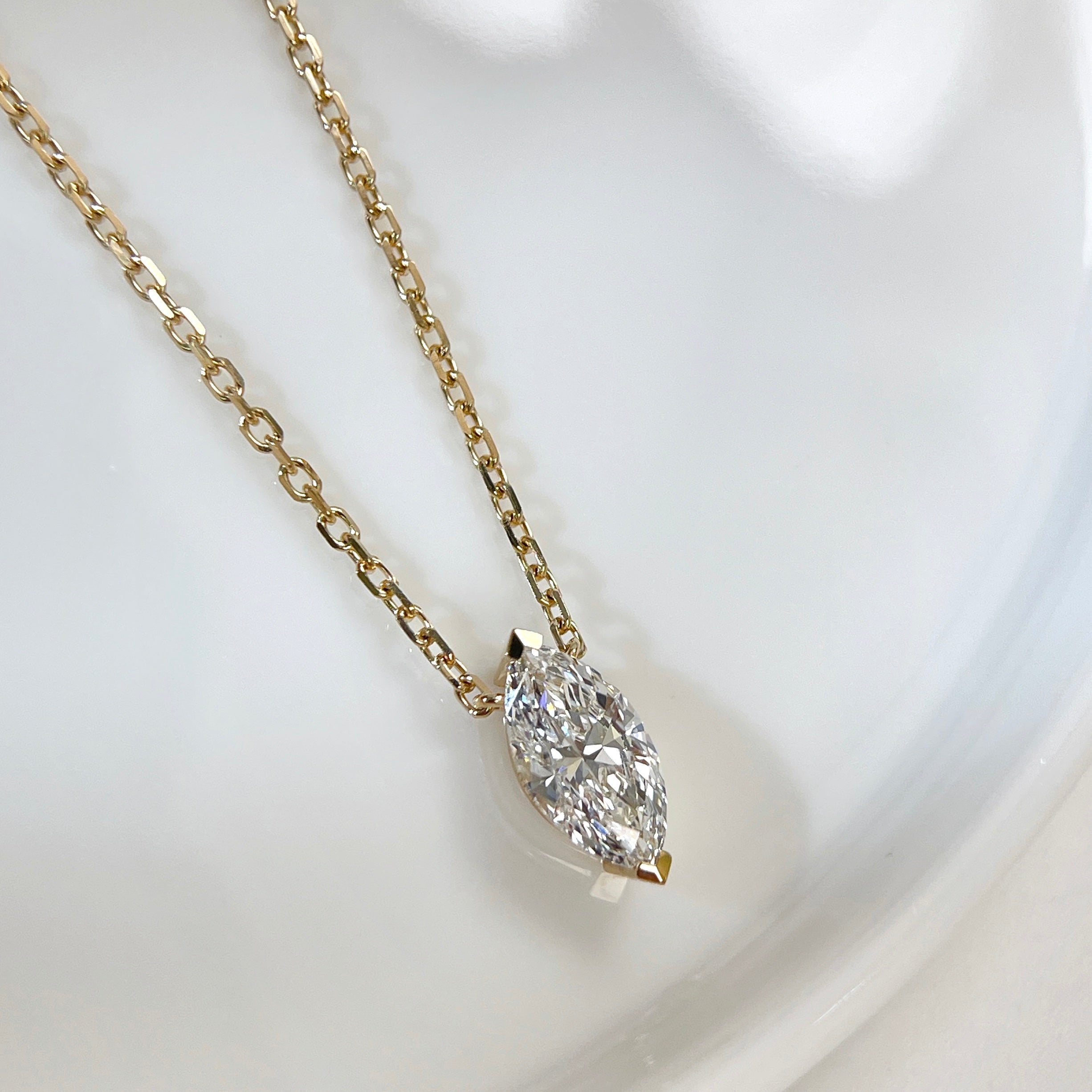 Close-up of a 1 carat marquise lab grown diamond necklace in 18K yellow gold.