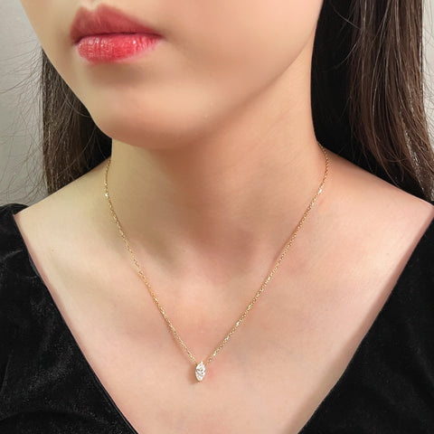 Side-profile view of a model wearing a 1 carat marquise lab grown diamond necklace in 18K yellow gold.