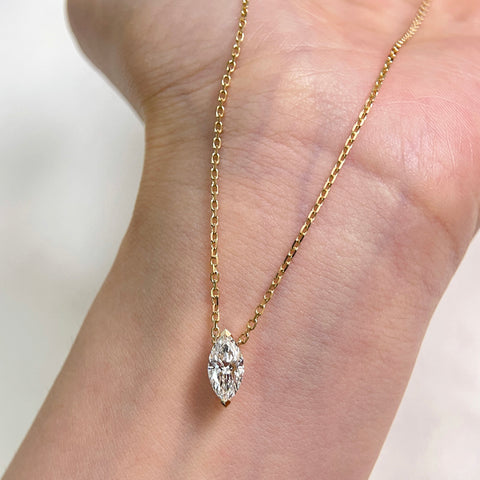 A 1 carat marquise lab grown diamond necklace in 18K yellow gold displayed on a hand.