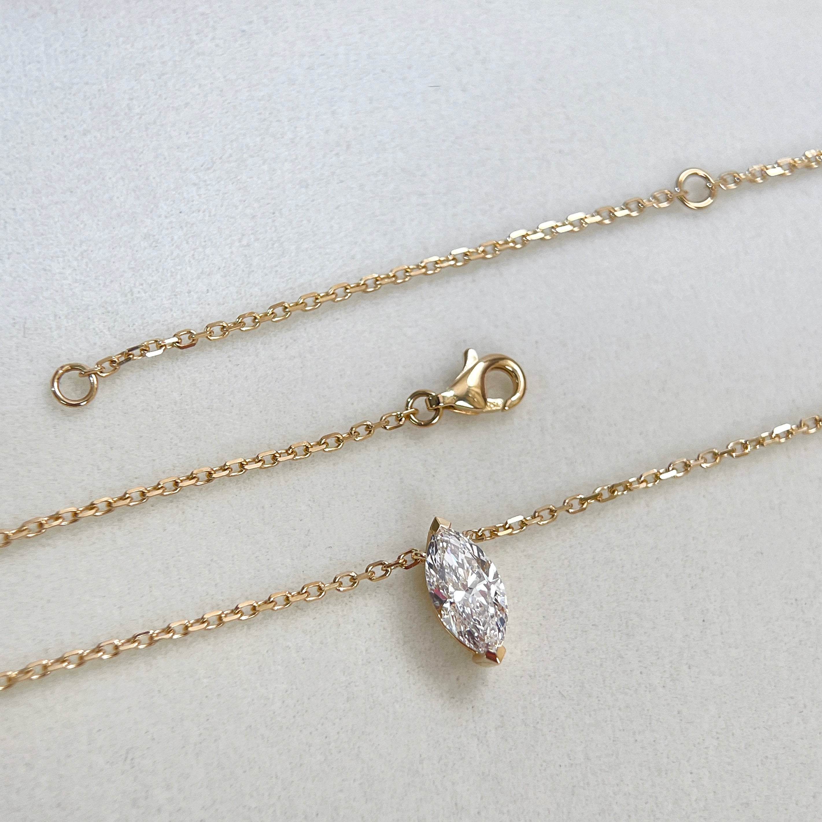Chain and clasp detail of a 1 carat marquise lab grown diamond necklace in 18K yellow gold.