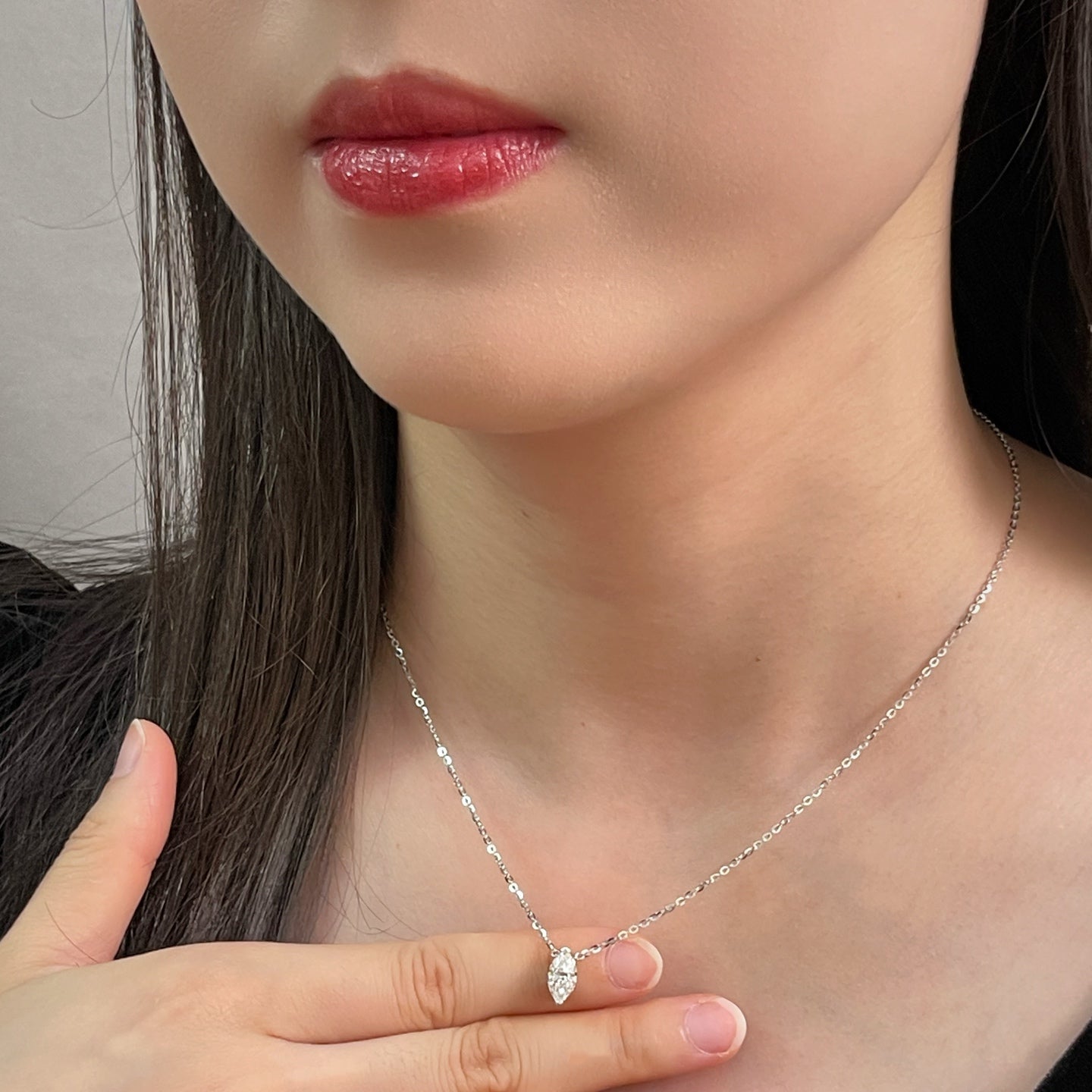 Model holding a 1 carat marquise lab grown diamond necklace in S925 sterling silver.
